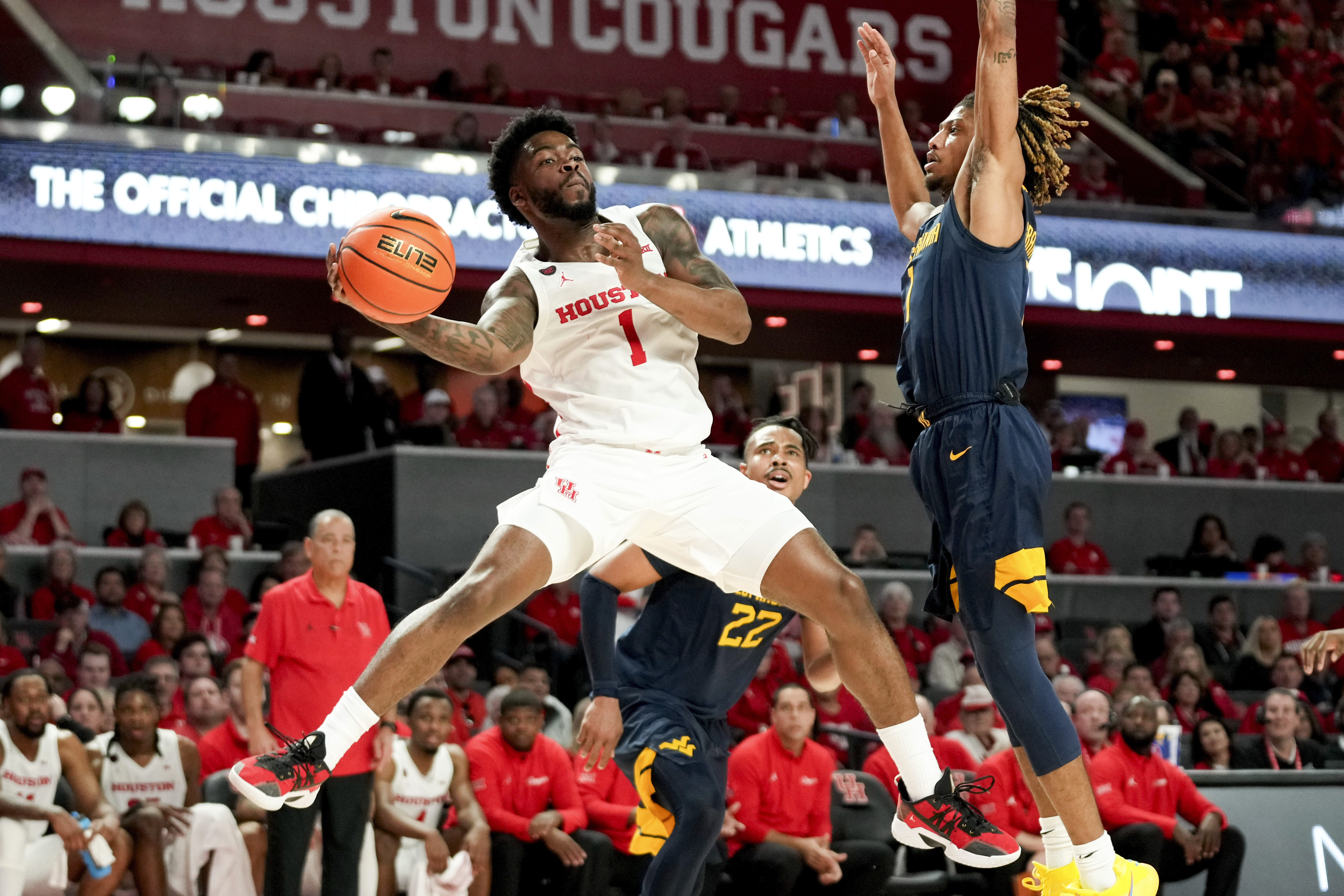 Houston guard Jamal Shead (1) passes as West Virginia guard Noah Farrakhan defends during the second half of an NCAA college basketball game Saturday Jan. 6, 2024, in Houston. 