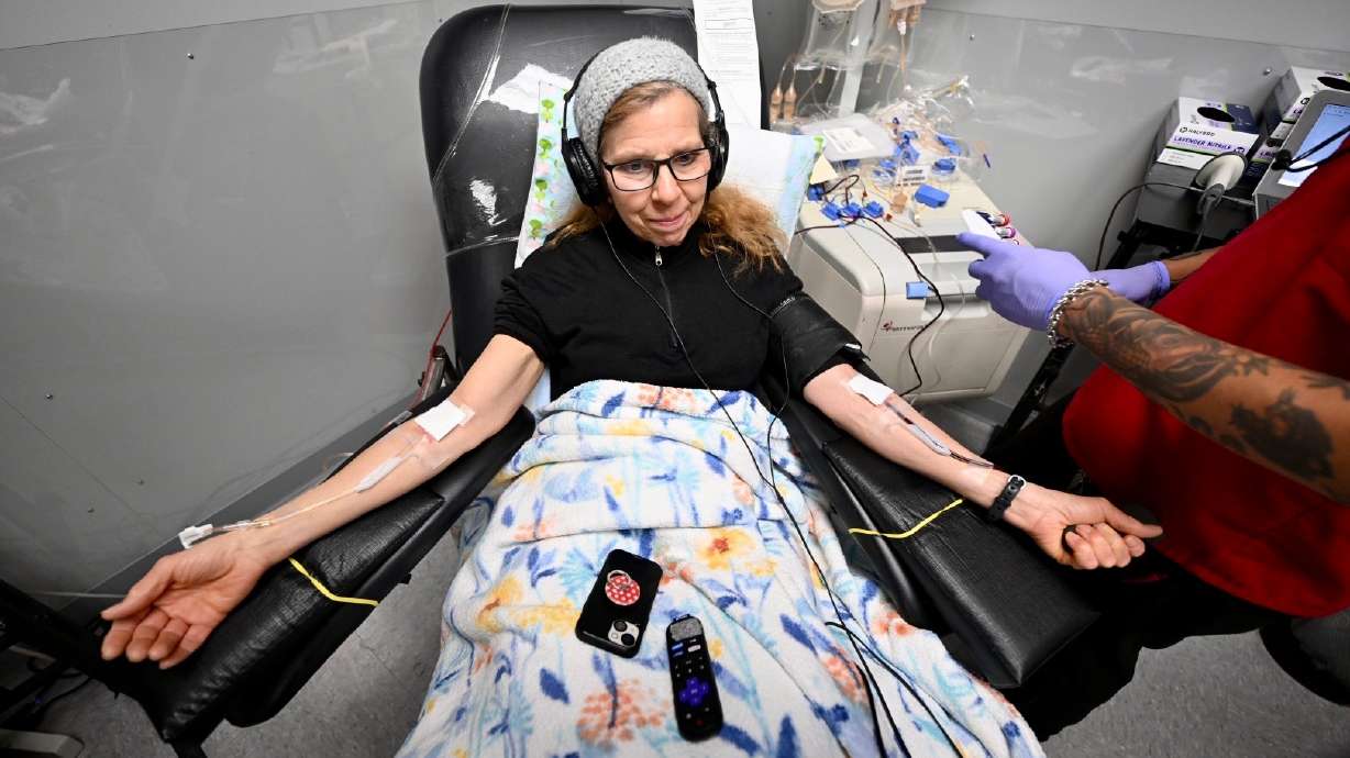 Jill Baker, watches a movie as Jonathan Guillen, collection specialist, assists her with her blood donation at the American Red Cross location in Murray, on Monday.