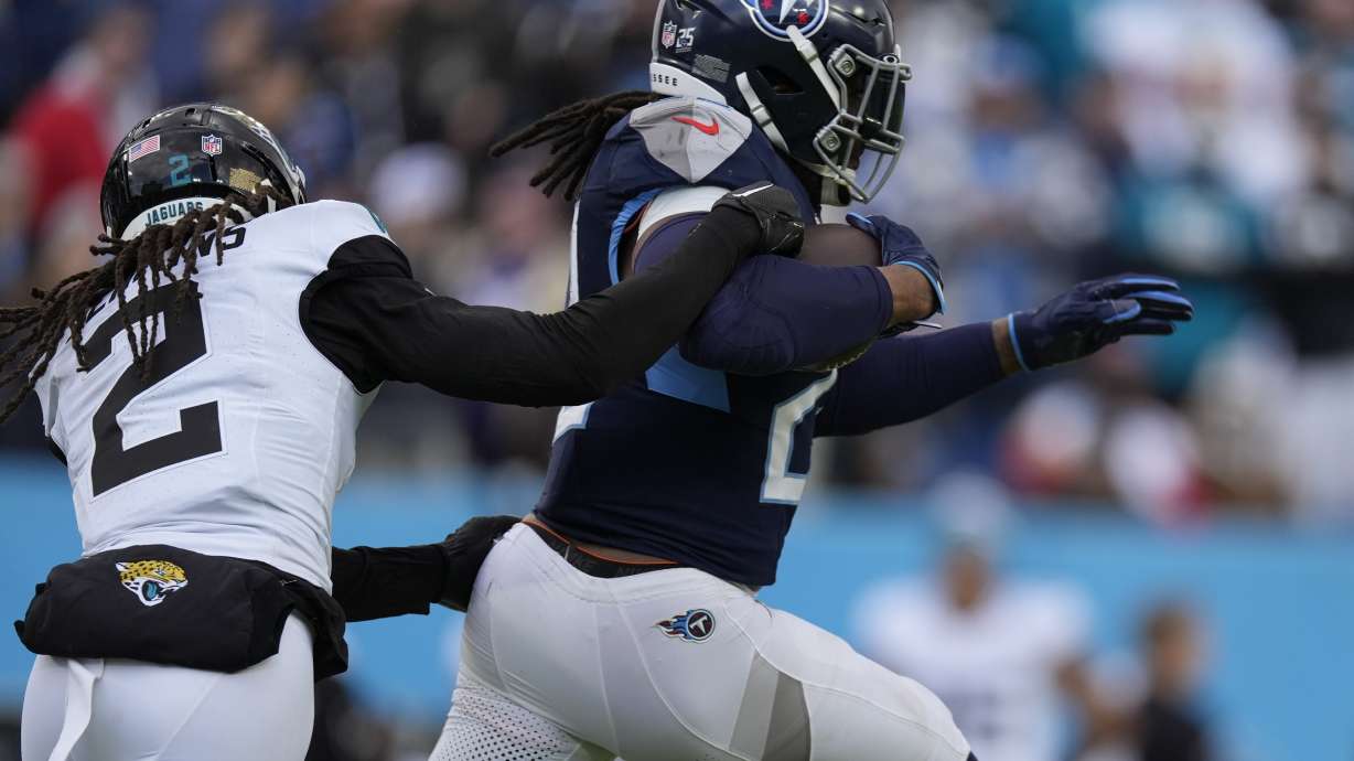 Tennessee Titans running back Derrick Henry, right, is tackled by Jacksonville Jaguars safety Rayshawn Jenkins, left, after a long gain during the second half of an NFL football game Sunday, Jan. 7, 2024, in Nashville, Tenn.