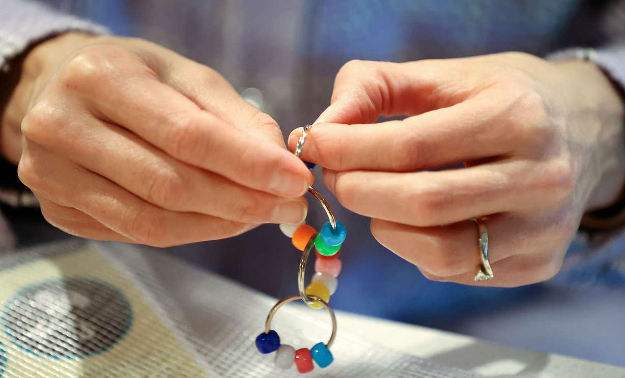 First lady Abby Cox makes a fidget toy as part of a Generus mental health and emotional fluency kit for a service project during a Why We Serve symposium at the Delta Center in Salt Lake City on Monday.
