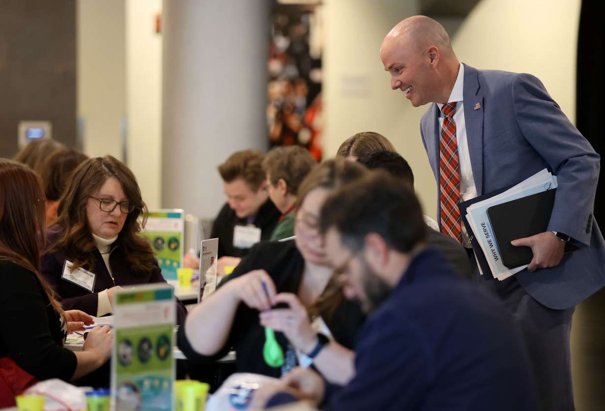 Gov. Spencer Cox checks in on people making Generus mental health and emotional fluency kits as part of a service project during a Why We Serve symposium at the Delta Center in Salt Lake City on Monday.