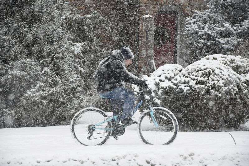 A cyclist navigates the sidewalk along State Road in North Adams, Mass., on Sunday afternoon, during the height of the snowstorm.