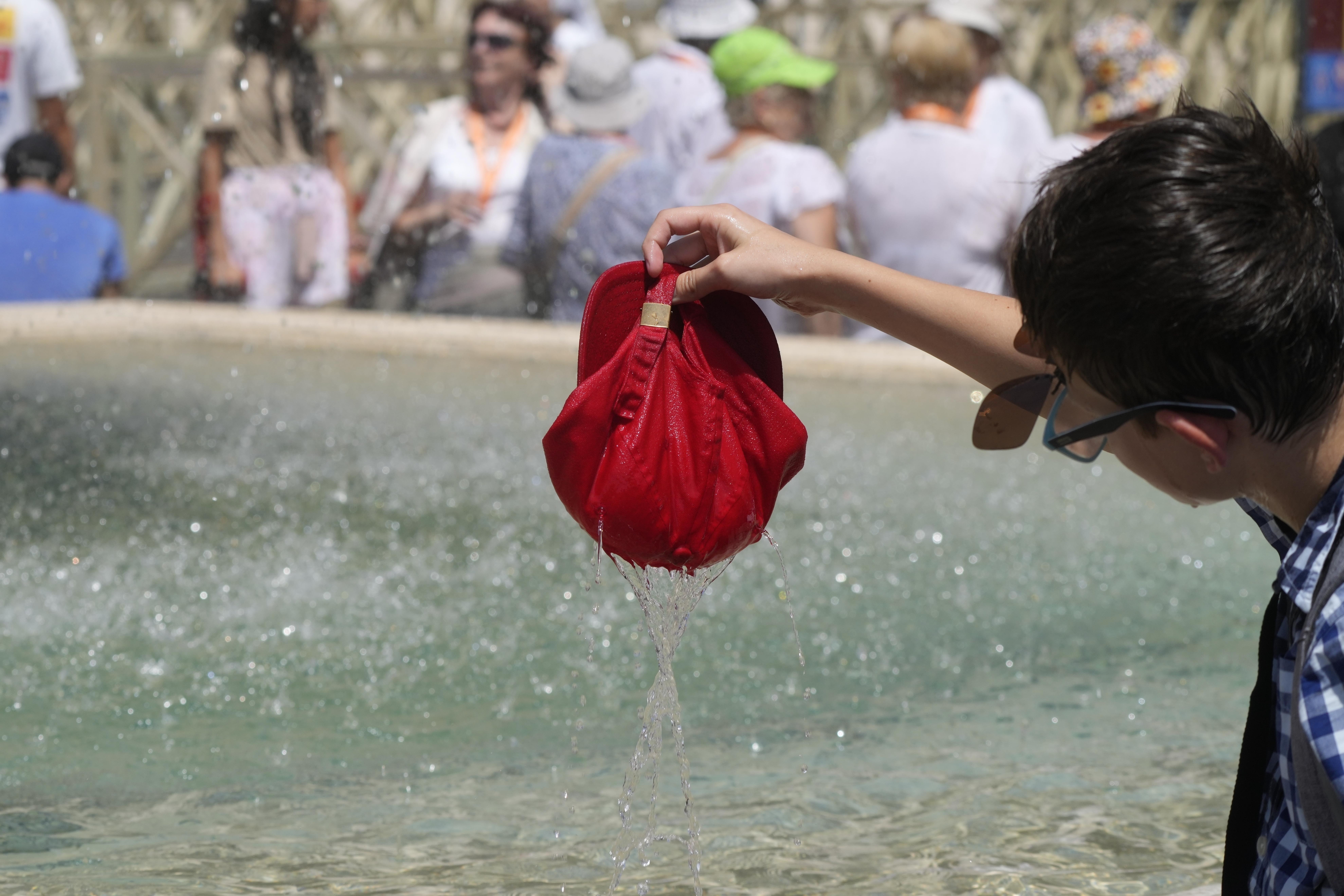 A child plunges his hat into a fountain on a hot day in St. Peter's Square at the Vatican July 16, 2023. Earth last year shattered global annual heat records, the European climate agency said Tuesday.