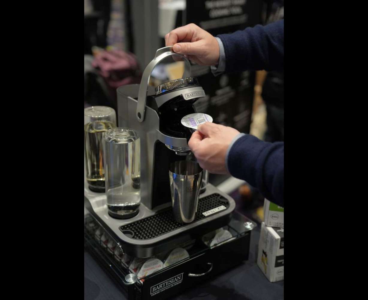 A person demonstrates the Bartesian Premier connected intelligent cocktail maker at the Bartesian booth at Pepcom ahead of the CES tech show Monday in Las Vegas.