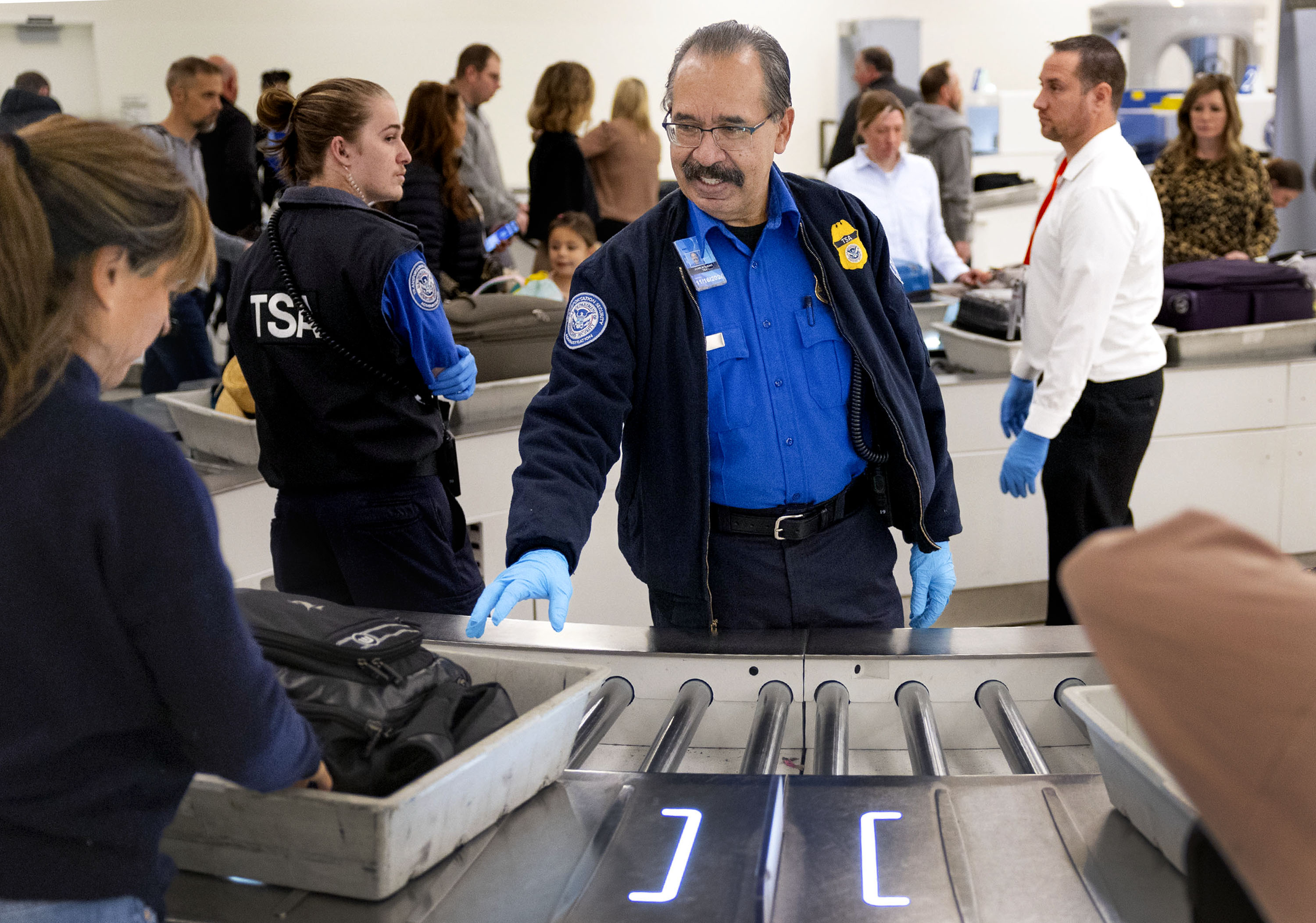 TSA officer Jaime Bueno helps travelers go through security at Salt Lake City International Airport on Monday, Dec. 18, 2023.