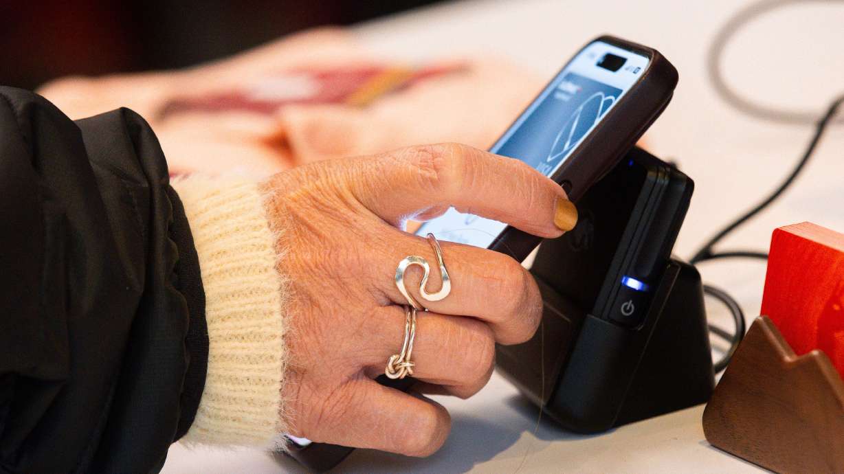 A customer uses Apple Pay to pay for items on Black Friday at Cotopaxi in Salt Lake City on Nov. 24, 2023. Trackers say consumer debt has topped $5 trillion in the U.S.