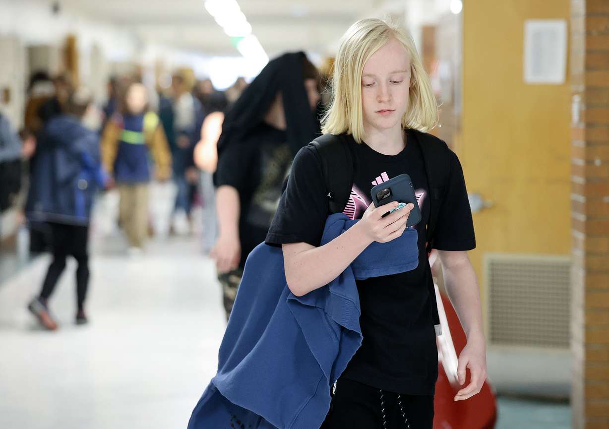Cruise Palmer uses his cellphone after school at Evergreen Junior High School in Millcreek on Wednesday. Phones are banned at Evergreen during the school day but are allowed after the final bell rings.