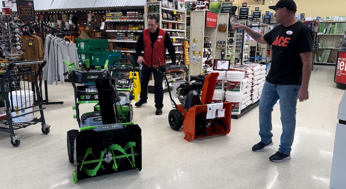 John Harris and an Ace Hardware employee get snowblowers out on the floor.