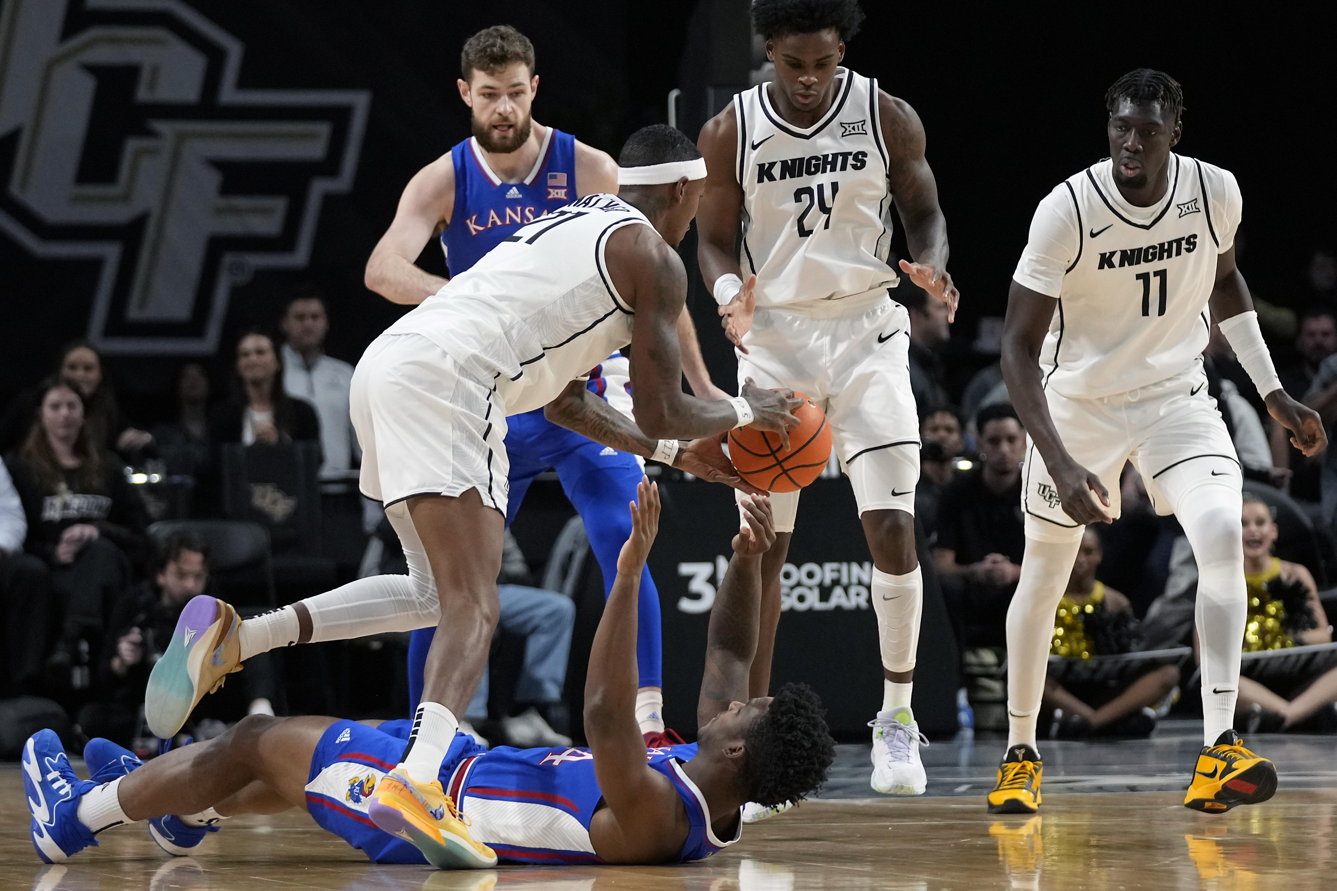 Central Florida forward C.J. Walker, front left, grabs the ball from Kansas forward K.J. Adams Jr. as he falls backward during the first half of an NCAA college basketball game, Wednesday, Jan. 10, 2024, in Orlando, Fla. 
