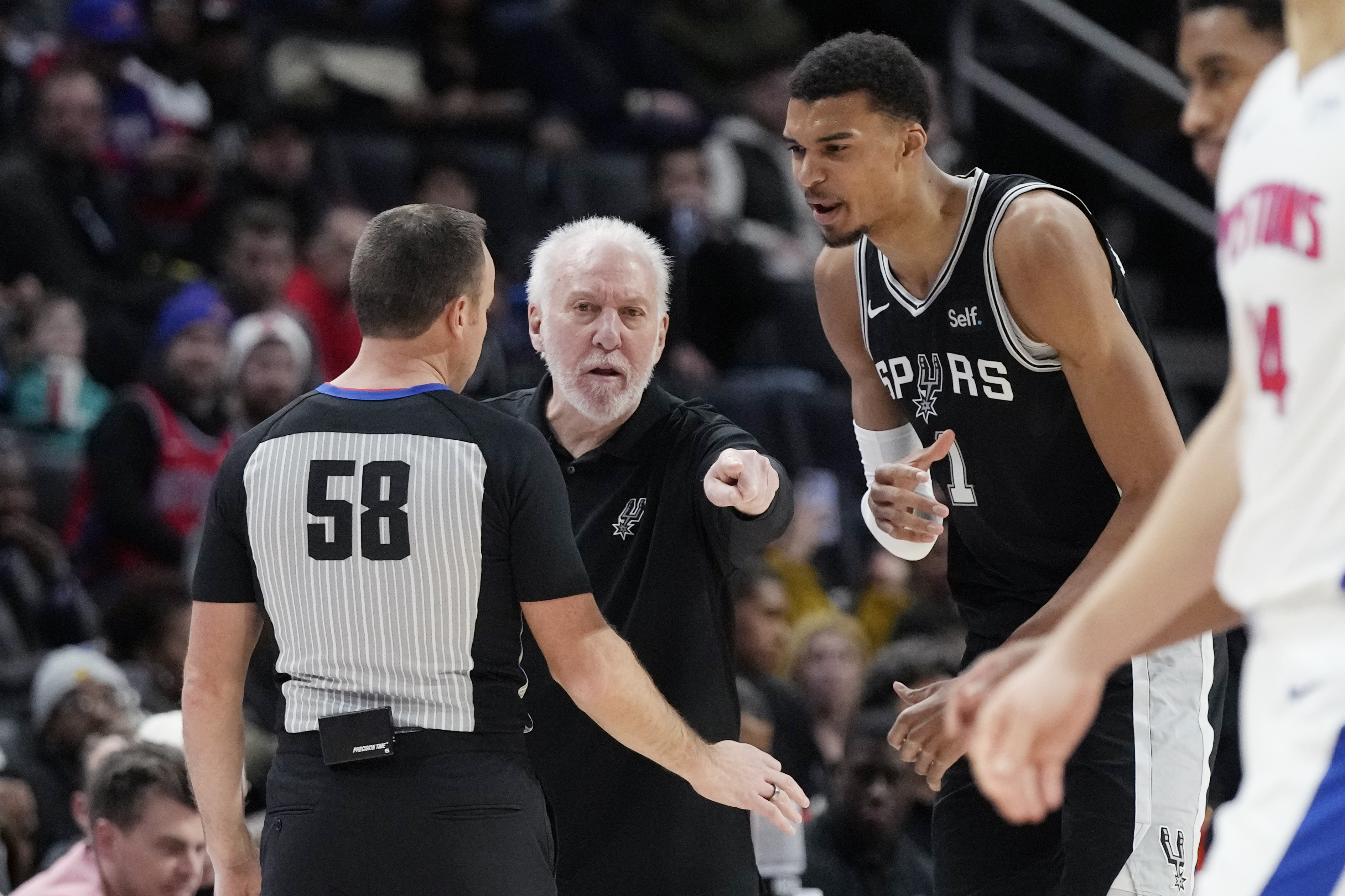 San Antonio Spurs head coach Gregg Popovich and center Victor Wembanyama (1) dispute a call with referee Josh Tiven (58) during the first half of an NBA basketball game against the Detroit Pistons, Wednesday, Jan. 10, 2024, in Detroit. 