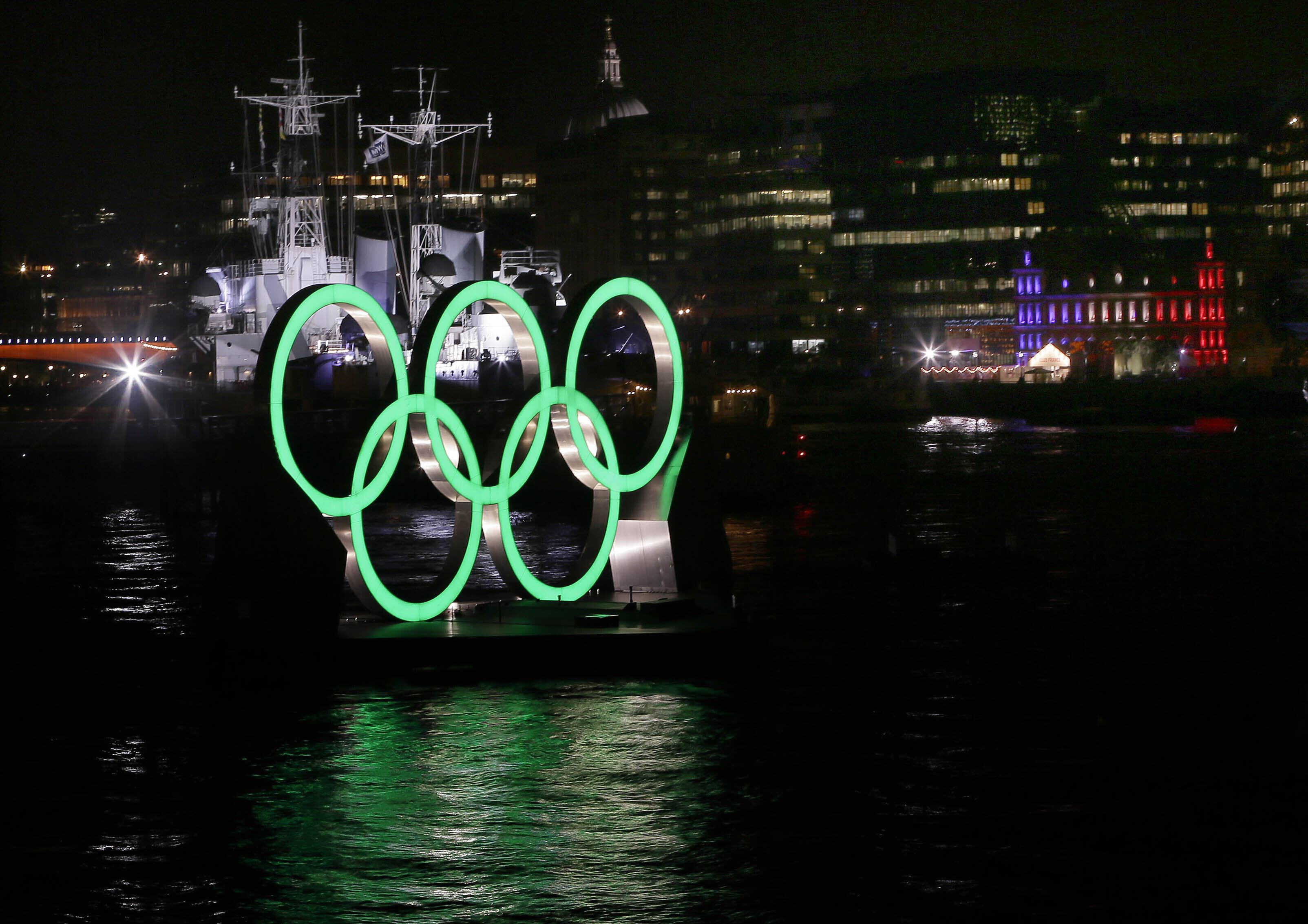 FILE - Olympic rings are illuminated in front of HMS Belfast on the River Thames, during the Opening Ceremony of the 2012 Summer Olympics, Friday, July 27, 2012, in London. The International Olympic Committee has signed Anheuser-Busch InBev as the first beer brand in the 40-year history of its sponsorship program, which earns billions of dollars for the organization and international sports. 