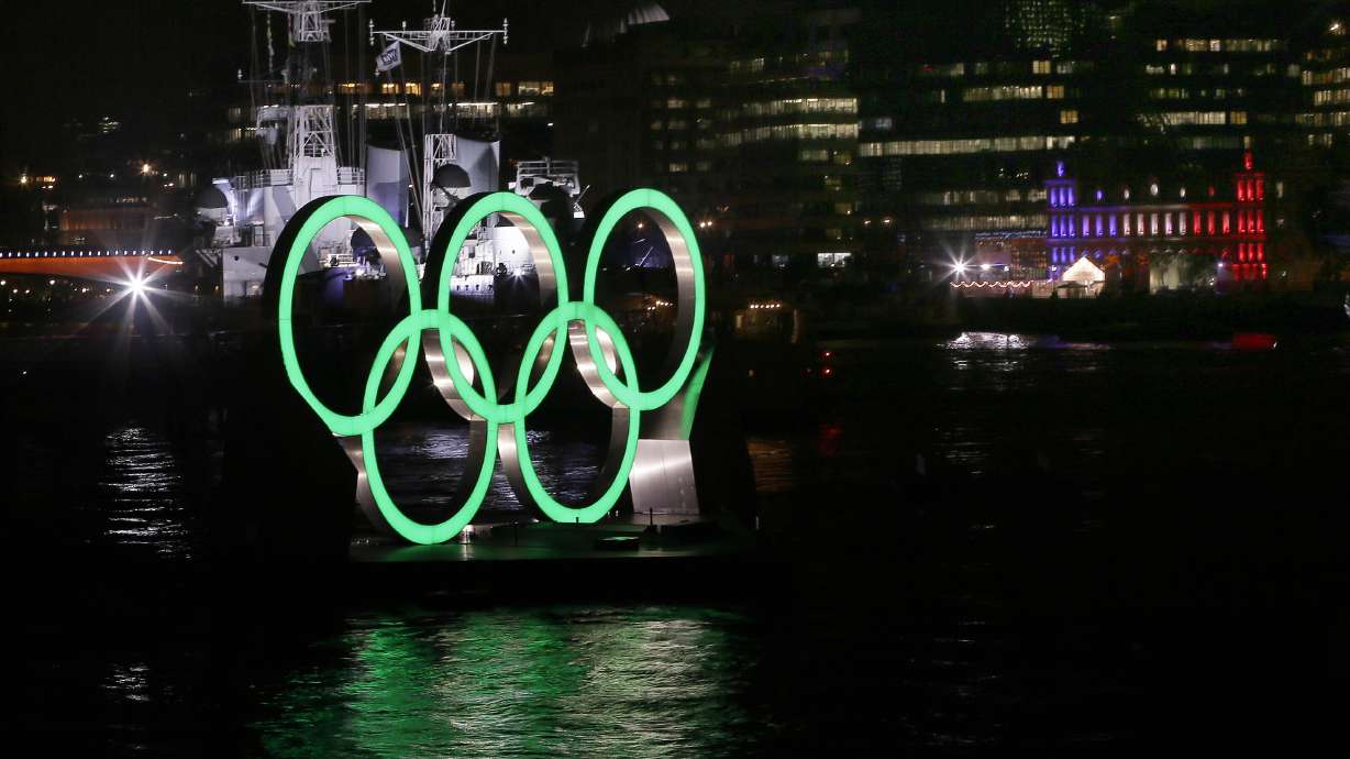 FILE - Olympic rings are illuminated in front of HMS Belfast on the River Thames, during the Opening Ceremony of the 2012 Summer Olympics, Friday, July 27, 2012, in London. The International Olympic Committee has signed Anheuser-Busch InBev as the first beer brand in the 40-year history of its sponsorship program, which earns billions of dollars for the organization and international sports.