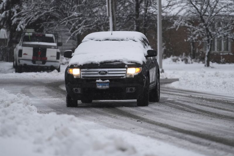 A commuter stops a car on the snowy road as a car window is covered by snow in Wheeling, Ill., Friday.