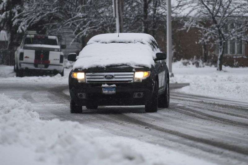 A commuter stops a car on the snowy road as a car window is covered by snow in Wheeling, Ill., Friday.
