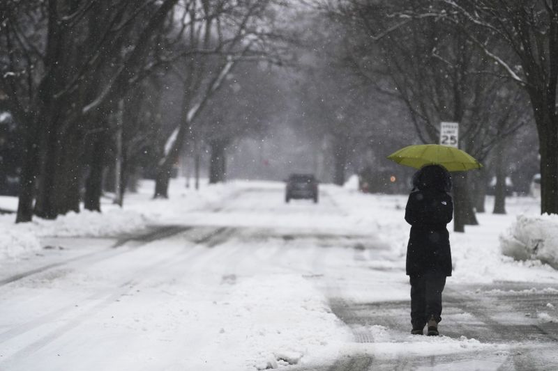 A woman walks with an umbrella during a snowy day in Wheeling, Ill., Friday.