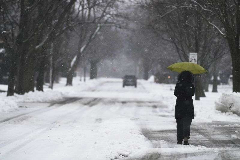 A woman walks with an umbrella during a snowy day in Wheeling, Ill., Friday.