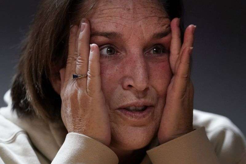 Shooting survivor Tammy Asselin clutches her face while reflecting on surviving a mass shooting by Army reservist Robert Card, during an interview, Dec. 27, 2023, in Lewiston, Maine.