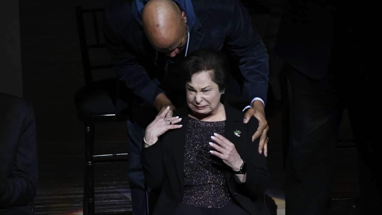 Former Chicago Bulls player Ron Harper, back, comforts Thelma Krause, widow of former Bulls general manager Jerry Krause, while the crowd boos when his name was announced during a Ring of Honor ceremony for the 1995-96 Bulls team ,during halftime of an NBA basketball game between the Bulls and the Golden State Warriors on Friday, Jan 12, 2024, in Chicago.