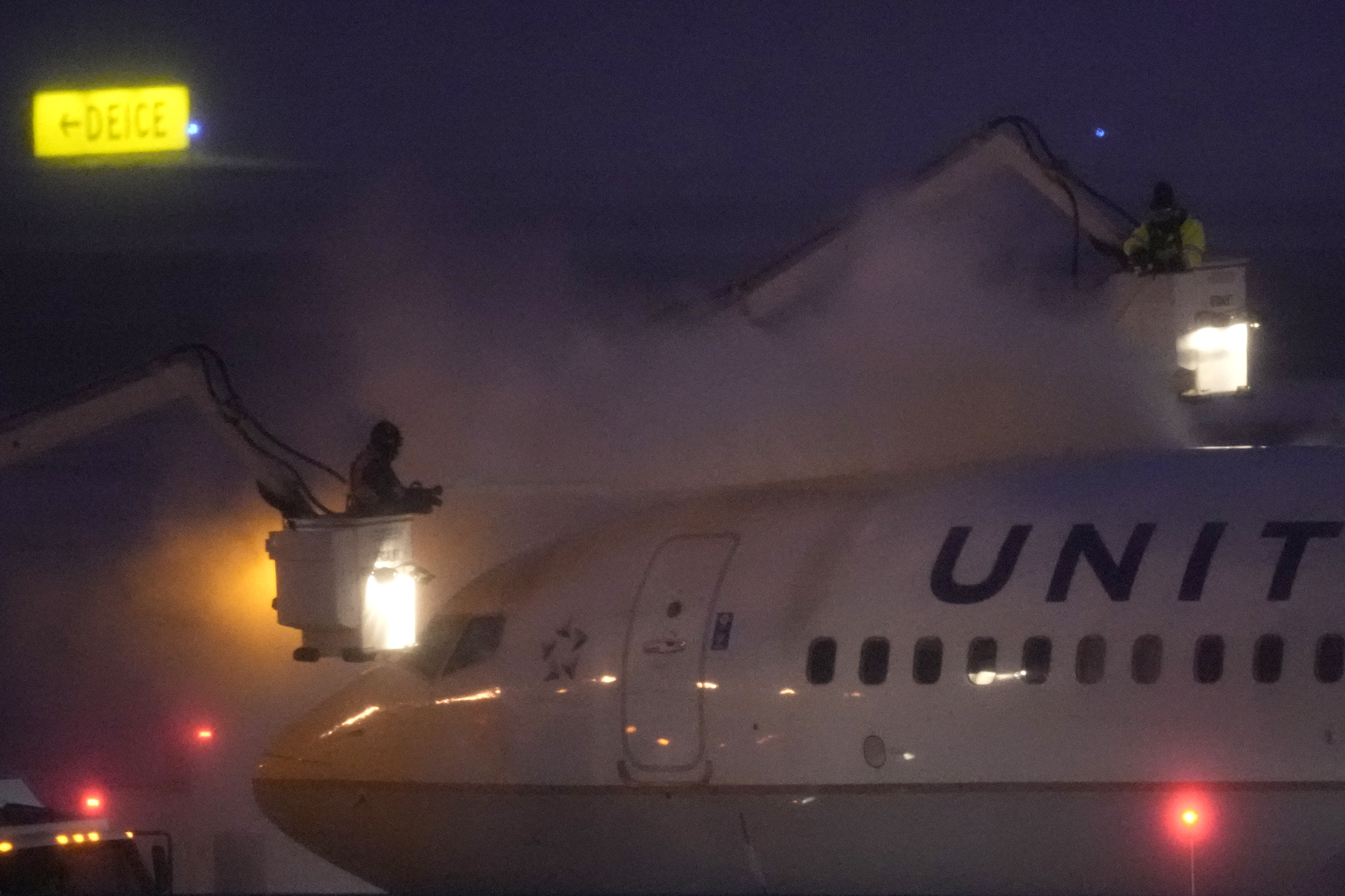 Workers brave near zero-degree weather and snow to spray deicer on a United Airlines jet Friday, Jan. 12, 2024, at Kansas City International airport in Kansas City, Mo. 