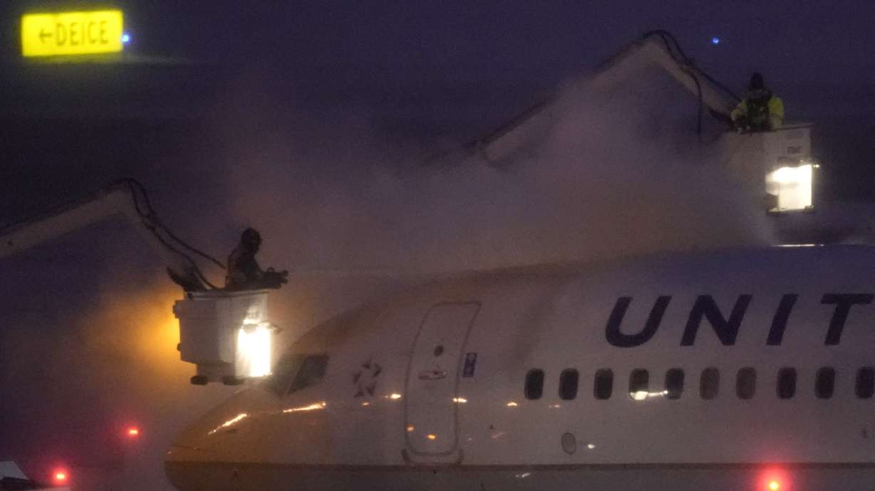 Workers brave near zero-degree weather and snow to spray deicer on a United Airlines jet Friday, Jan. 12, 2024, at Kansas City International airport in Kansas City, Mo.