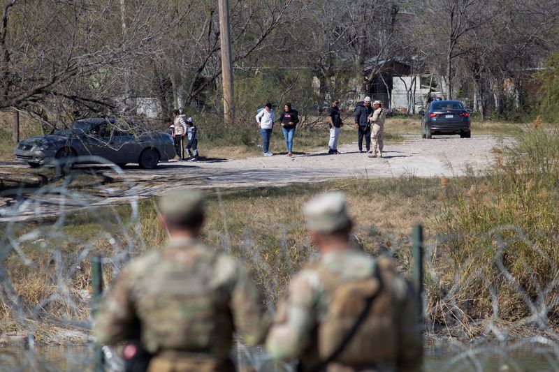 Texas National Guard troops watch a Mexican official prevent a group of people from entering the Rio Grande River across from Shelby Park at the U.S.-Mexico border in Eagle Pass, Texas, U.S., Jan. 12.