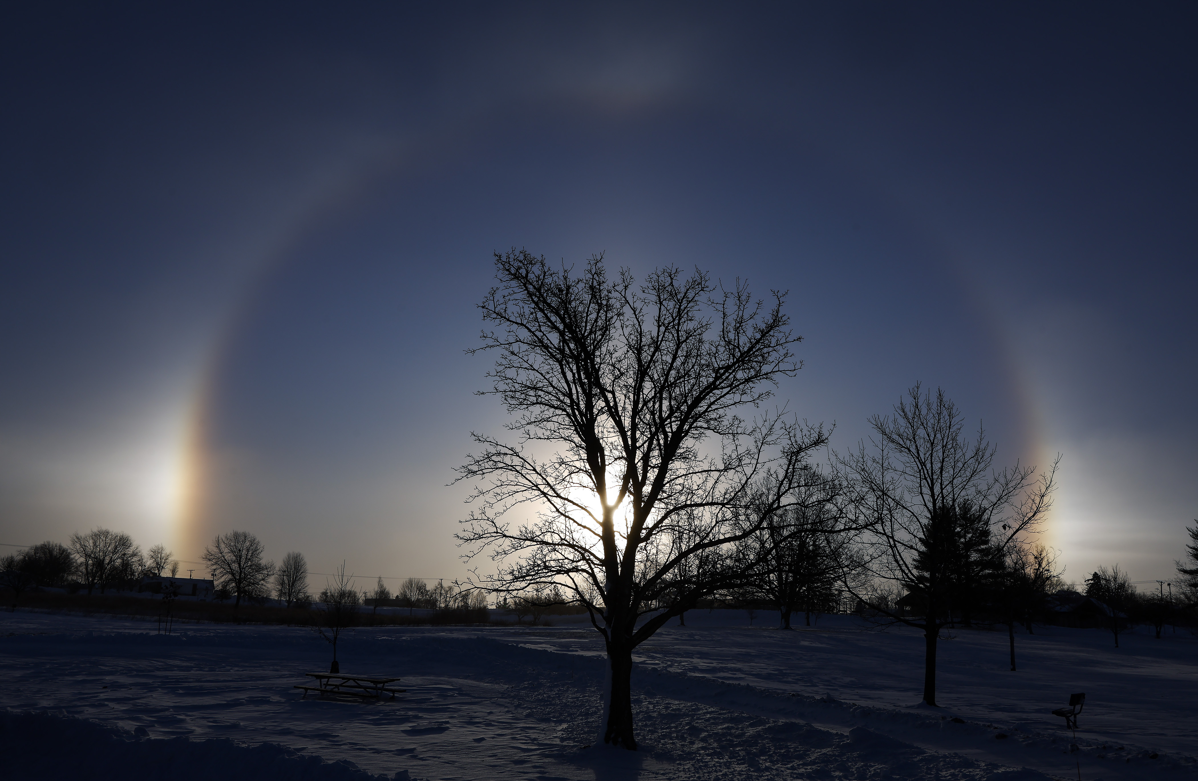 Sun dogs are seen on each side of the sun at Noelridge Park in northeast Cedar Rapids, Iowa, on Sunday. The optical illusions are caused by the refraction of sunlight by ice crystals in the atmosphere. 