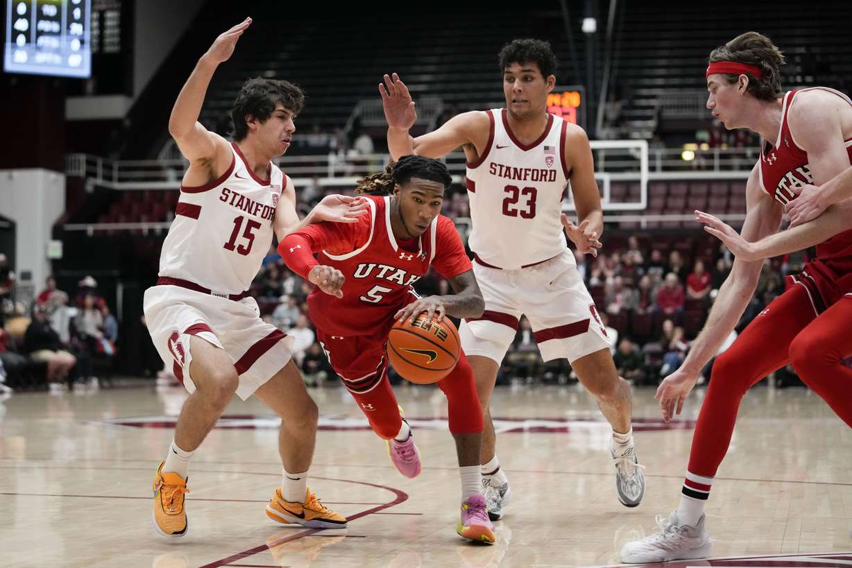 Utah guard Deivon Smith (5) dribbles between Stanford guard Benny Gealer (15) and forward Brandon Angel (23) during the first half of an NCAA college basketball game, Sunday, Jan. 14, 2024, in Stanford, Calif.