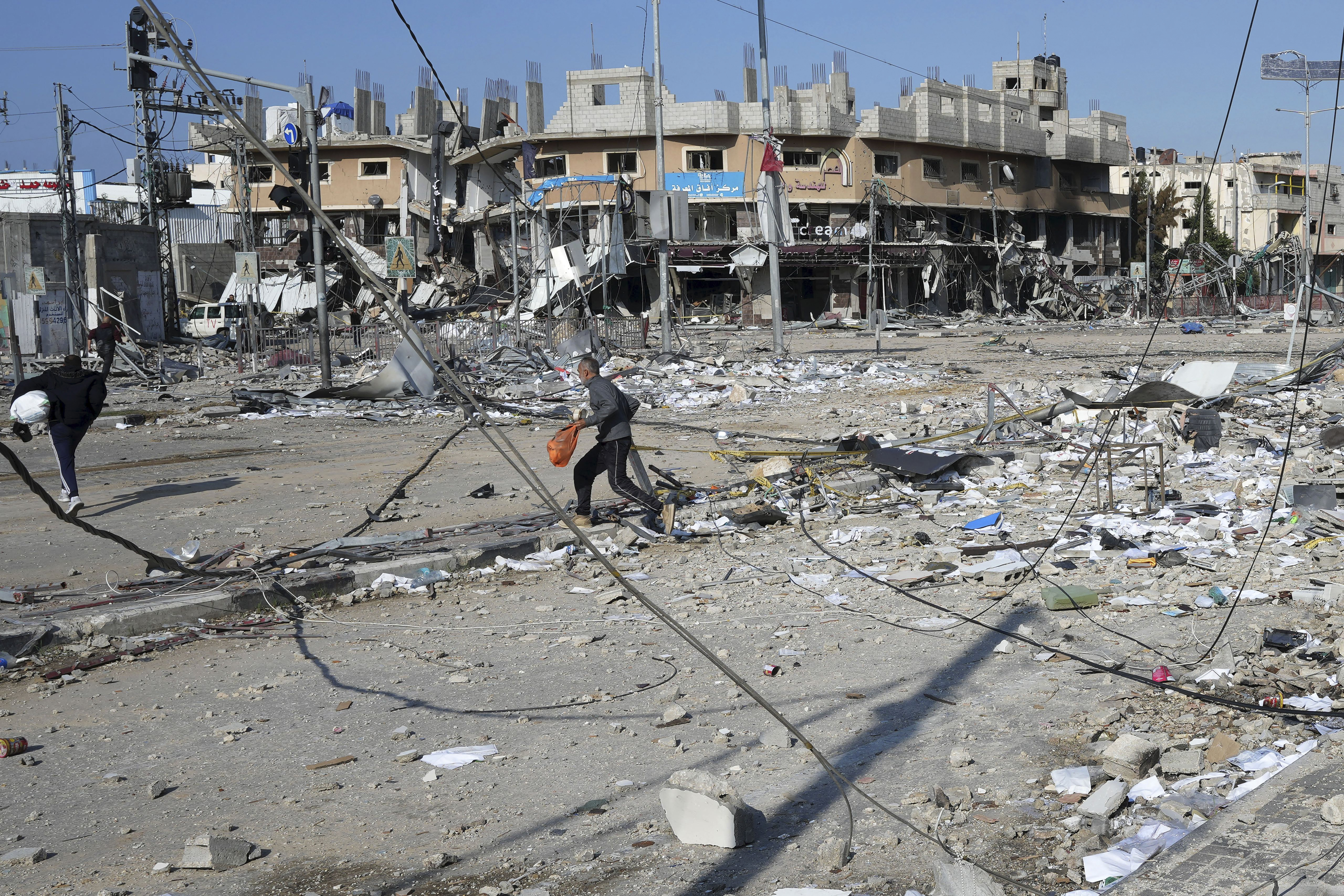 Palestinians walk through destruction by the Israeli bombardment in the Nusseirat refugee camp in Gaza Strip, Tuesday. A spokesman for Qatar's Foreign Ministry says medicine for dozens of hostages held by Hamas has reached the Gaza Strip.