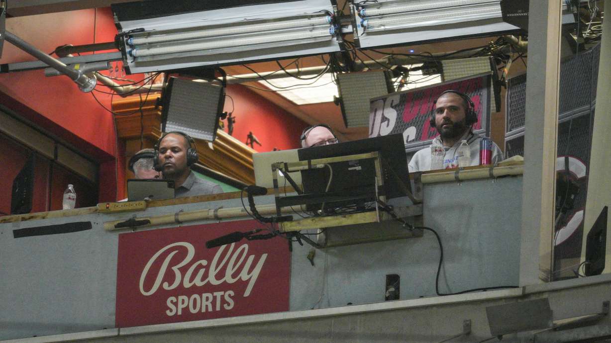 FILE - Cincinnati Reds' Joey Votto, right, sits in the broadcast booth with John Sadak, center right, and Barry Larkin, center left, during a baseball game against the St. Louis Cardinals Wednesday, Aug. 31, 2022, in Cincinnati. Amazon will partner with the Diamond Sports as part of a restructuring agreement as the largest owner of regional sports networks looks to emerge from bankruptcy. Diamond owns 18 networks under the Bally Sports banner. Those networks have the rights to 37 professional teams — 11 baseball, 15 NBA and 11 NHL.