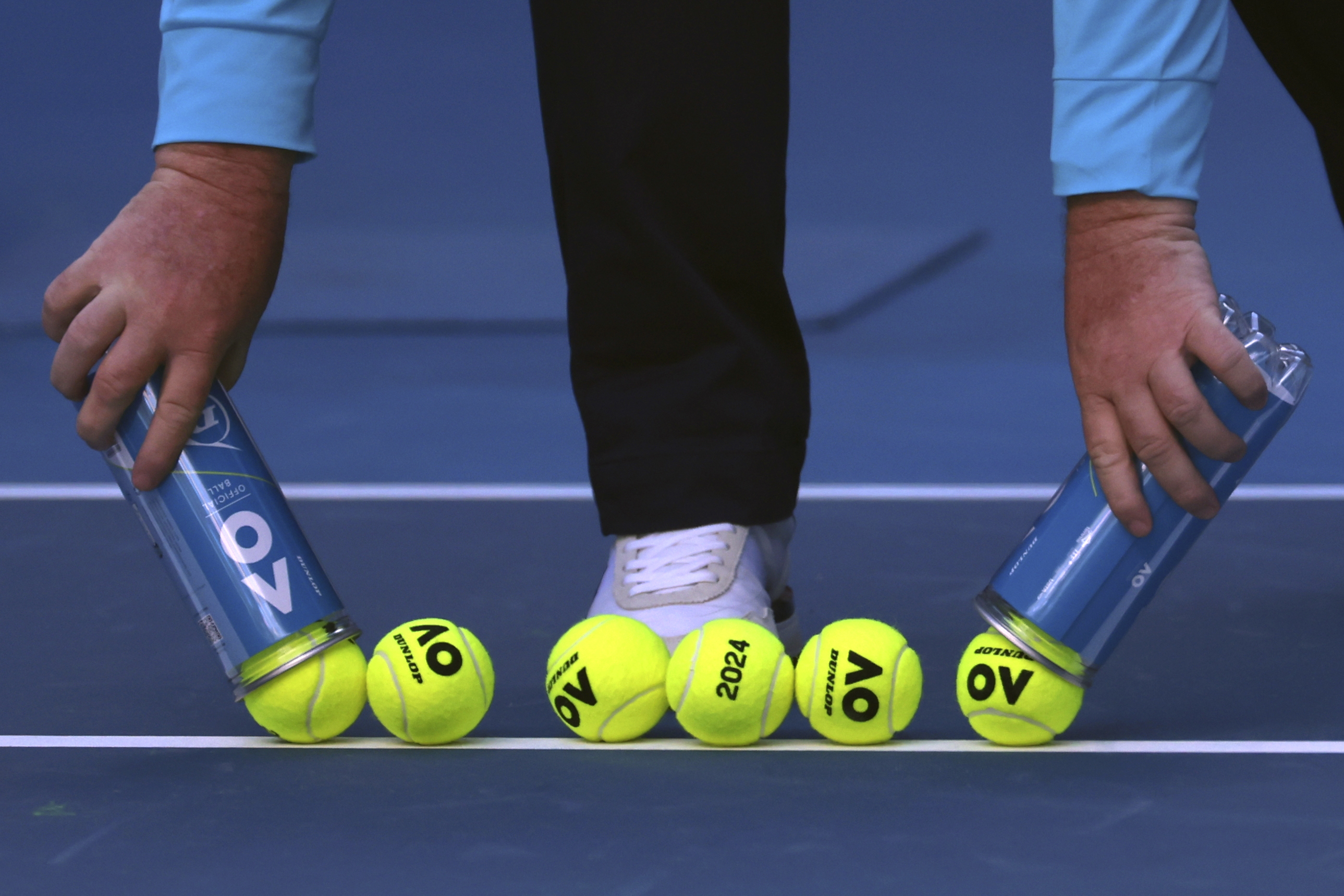 A court official lays out new balls for the Camila Giorgi of Italy and Victoria Azarenka of Belarus first round match at the Australian Open tennis championships at Melbourne Park, Melbourne, Australia, Tuesday, Jan. 16, 2024. 