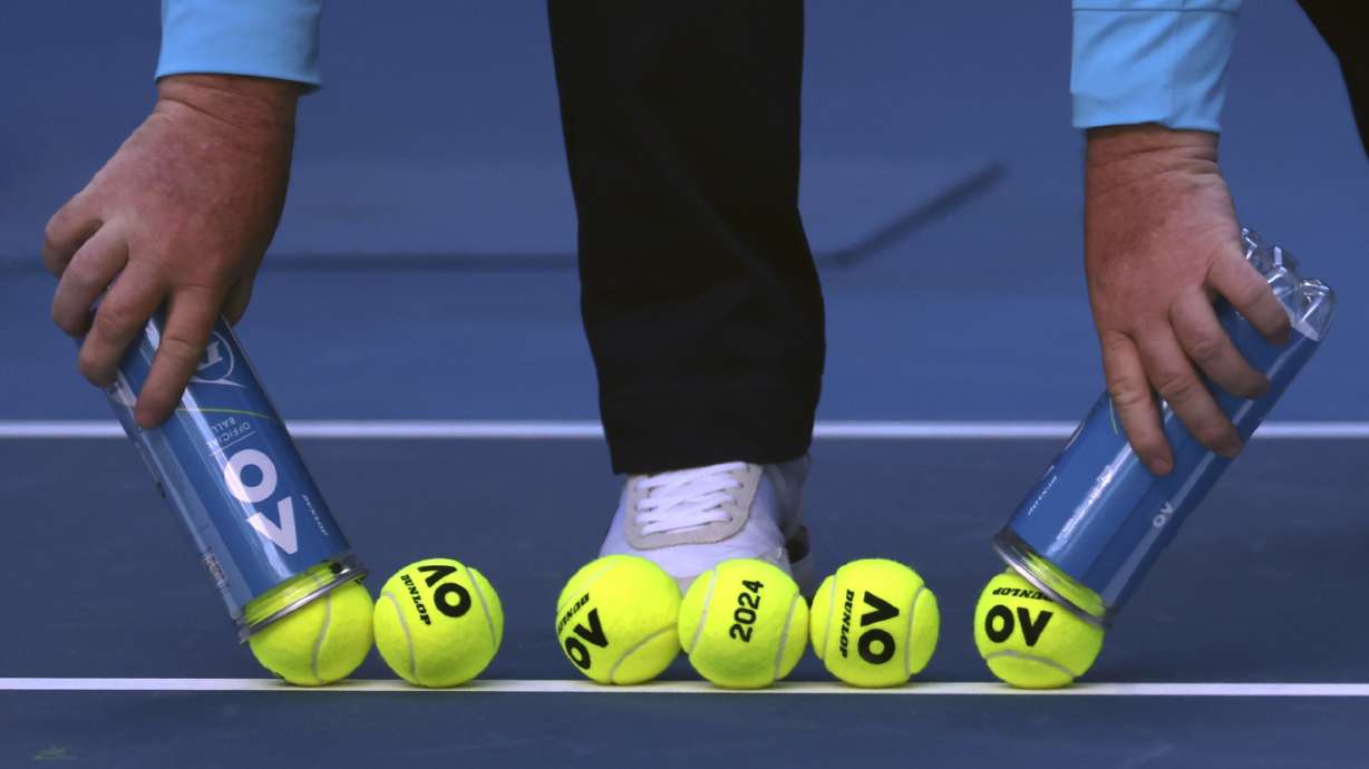 A court official lays out new balls for the Camila Giorgi of Italy and Victoria Azarenka of Belarus first round match at the Australian Open tennis championships at Melbourne Park, Melbourne, Australia, Tuesday, Jan. 16, 2024.