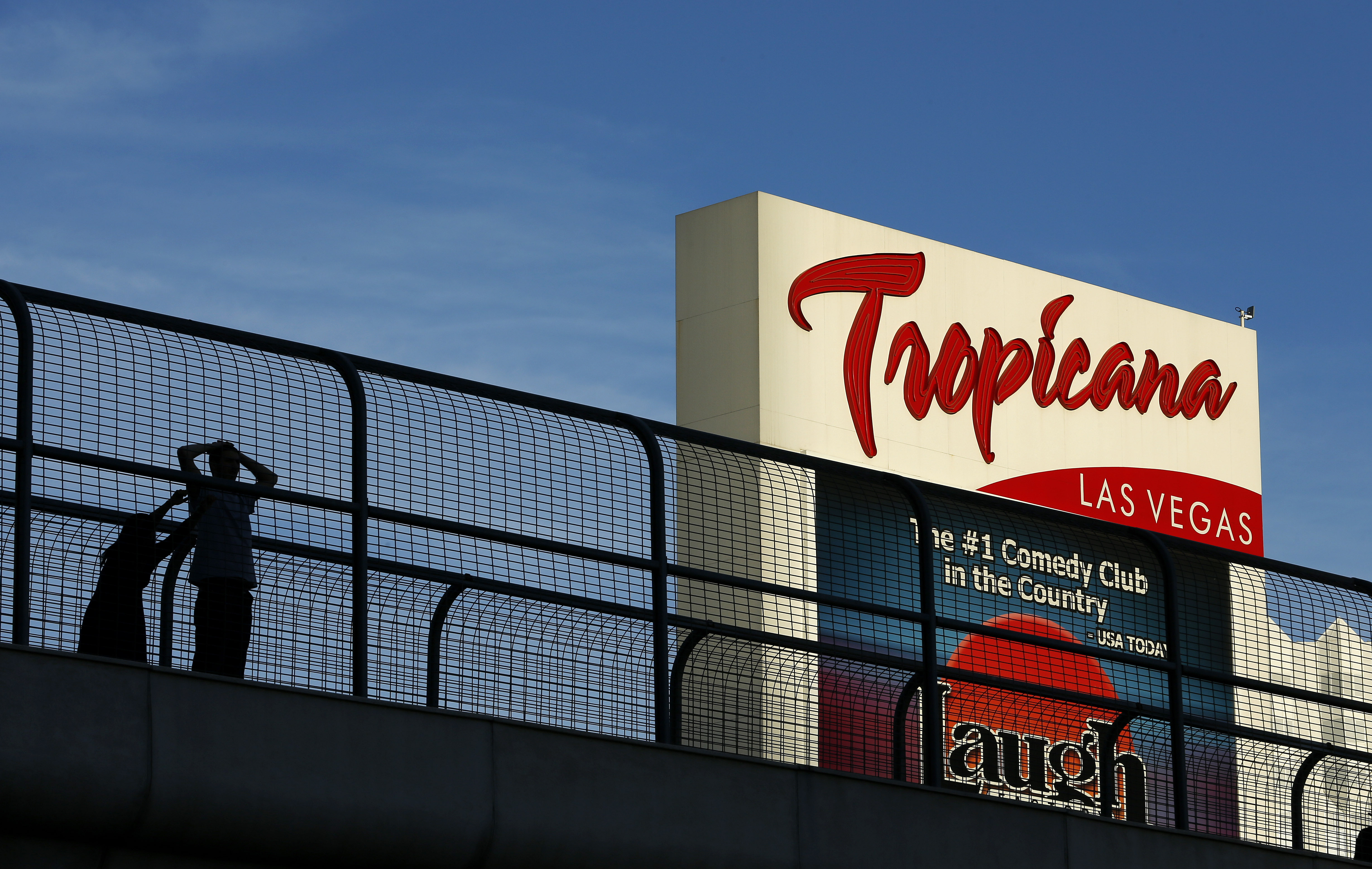 People stand on a pedestrian bridge by the Tropicana Hotel and Casino in Las Vegas, Aug. 4, 2015. Stopping or standing is prohibited on Las Vegas Strip pedestrian bridges after a new ordinance took effect Tuesday.
