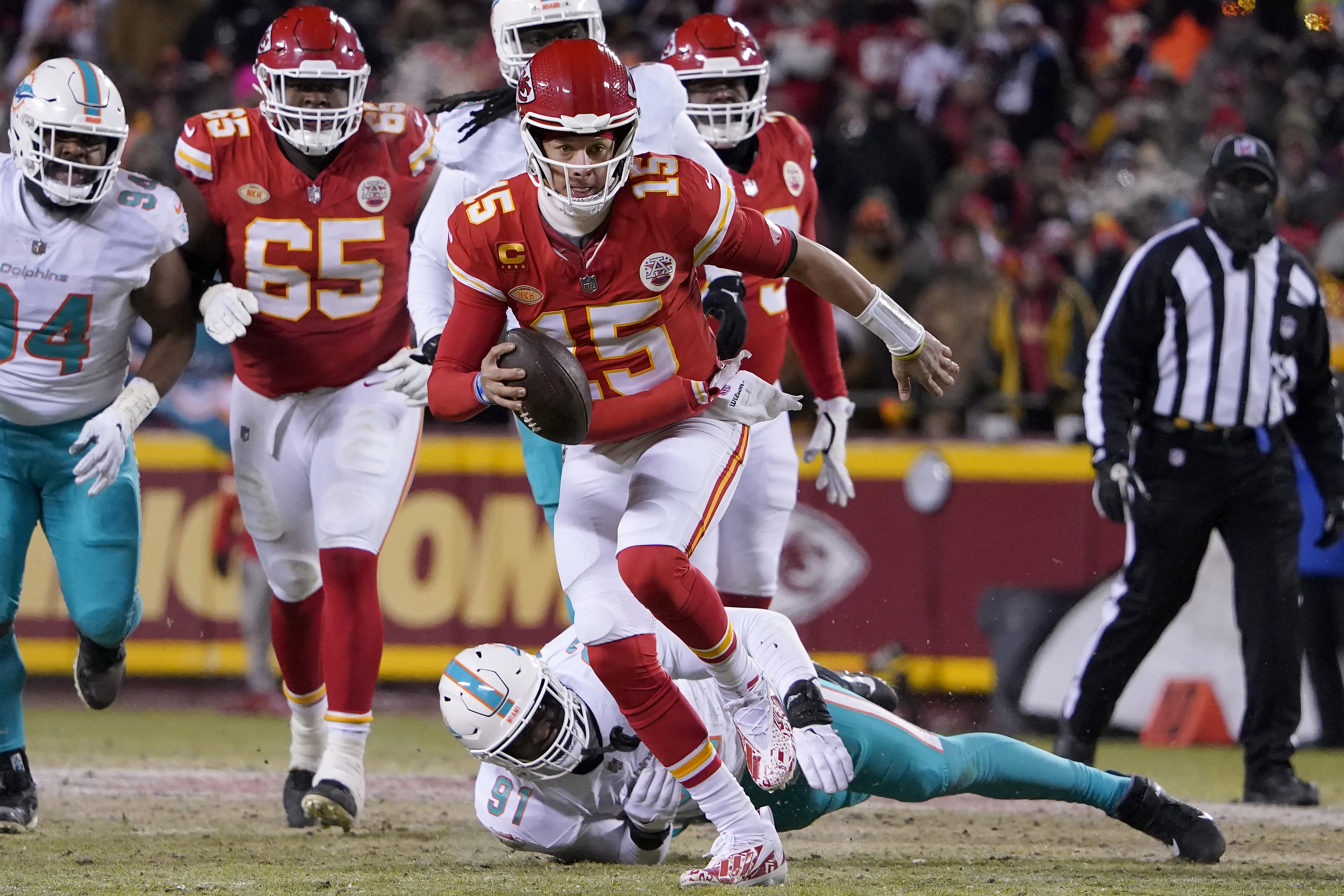 Kansas City Chiefs quarterback Patrick Mahomes (15) runs in front of Miami Dolphins defensive end Emmanuel Ogbah (91) during the first half of an NFL wild-card playoff football game Saturday, Jan. 13, 2024, in Kansas City, Mo. 