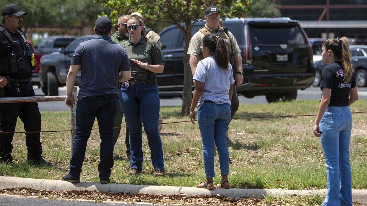 A law enforcement officer speaks with people outside Uvalde High School after shooting a was reported earlier in the day at Robb Elementary School, May 24, 2022, in Uvalde, Texas. The Justice Department Thursday released findings of an investigation into the 2022 school shooting.