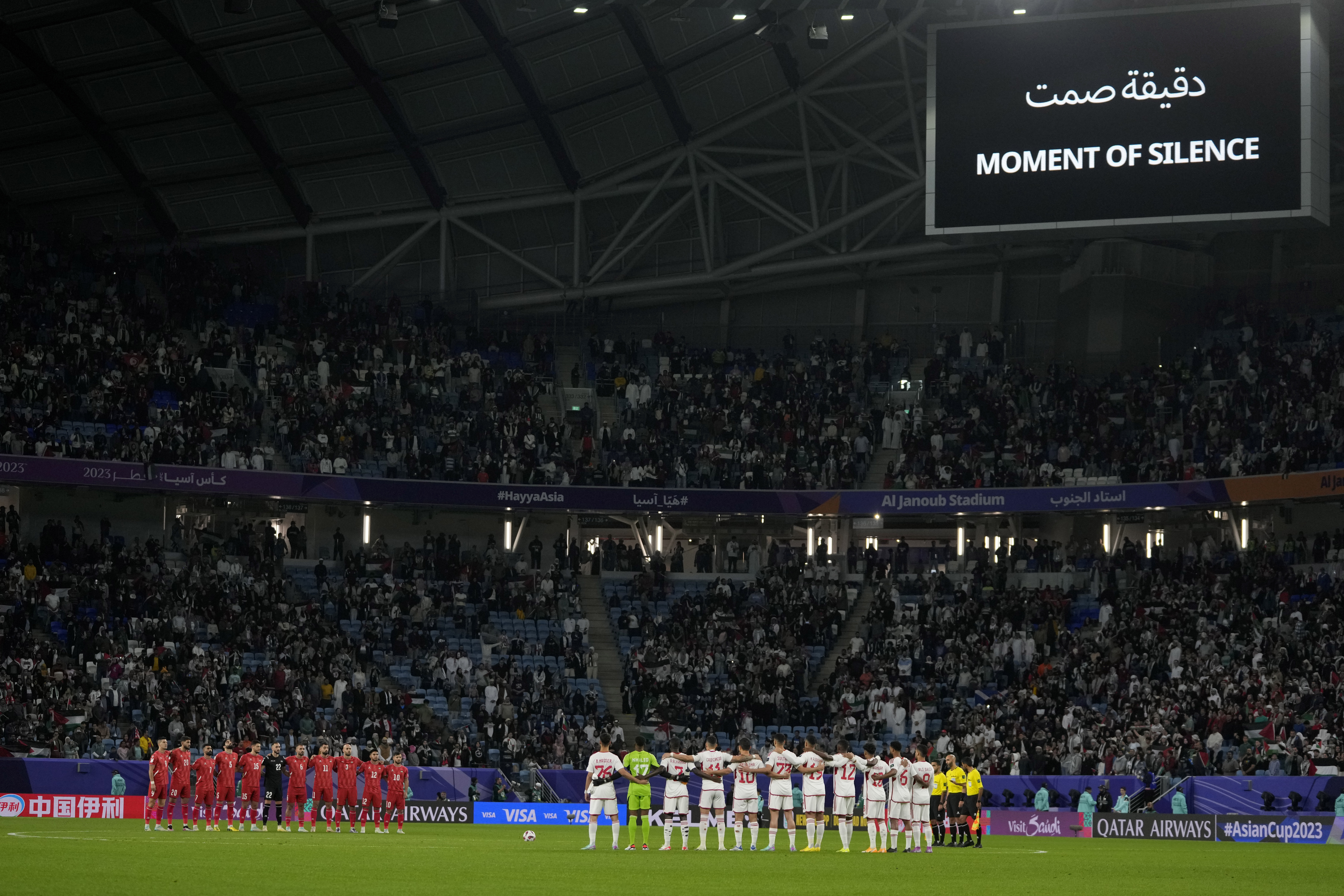Players of Palestine, left, and United Arab Emirates, right, stand as they observe the moment of silence prior to the start of the Asian Cup Group C soccer match between Palestine and United Arab Emirates at Al Janoub Stadium in Al Wakrah, Qatar, Thursday, Jan. 18, 2024. 