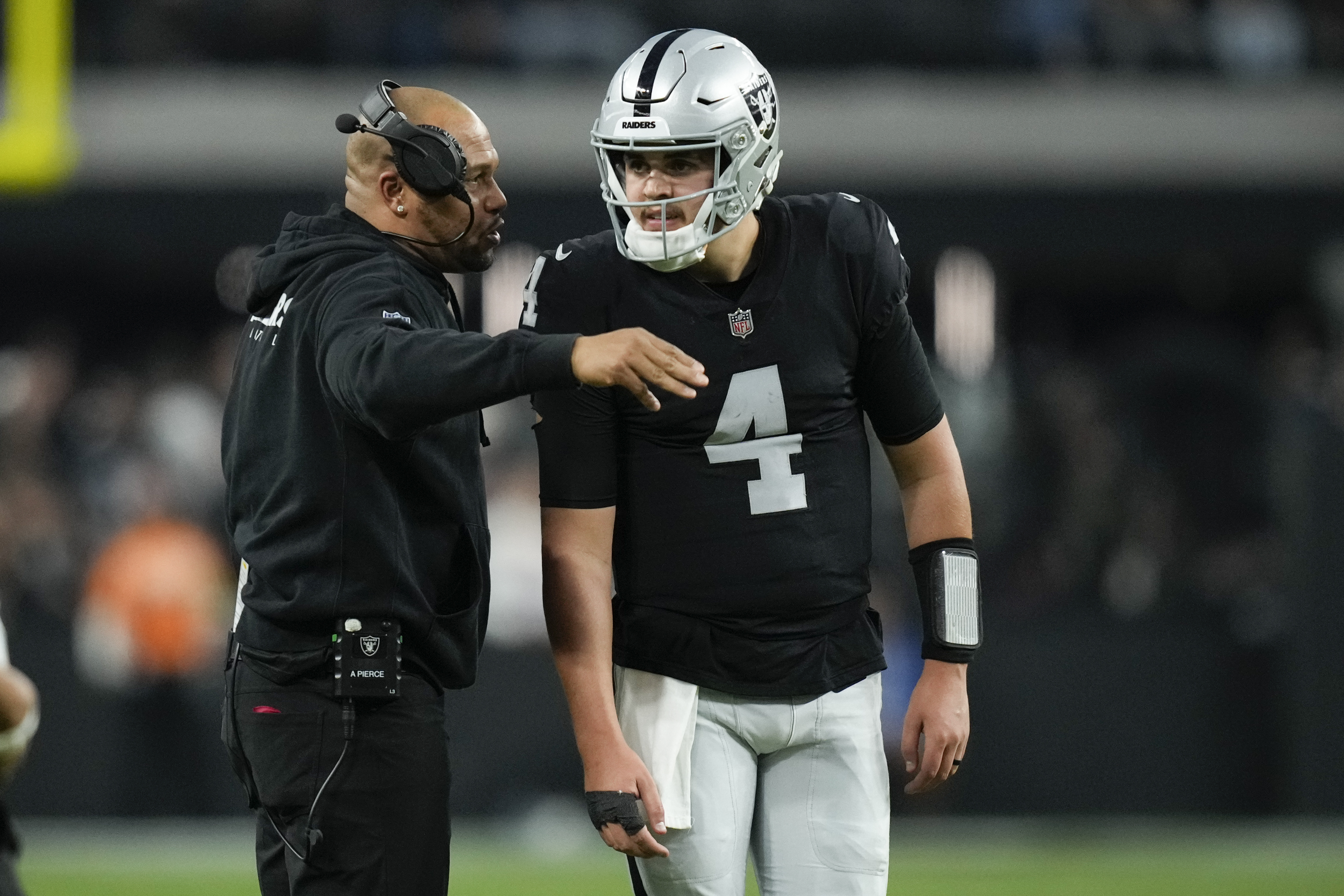 Las Vegas Raiders quarterback Aidan O'Connell (4) talks to interim head coach Antonio Pierce during the second half of an NFL football game against the Denver Broncos, Sunday, Jan. 7, 2024 in Las Vegas. 