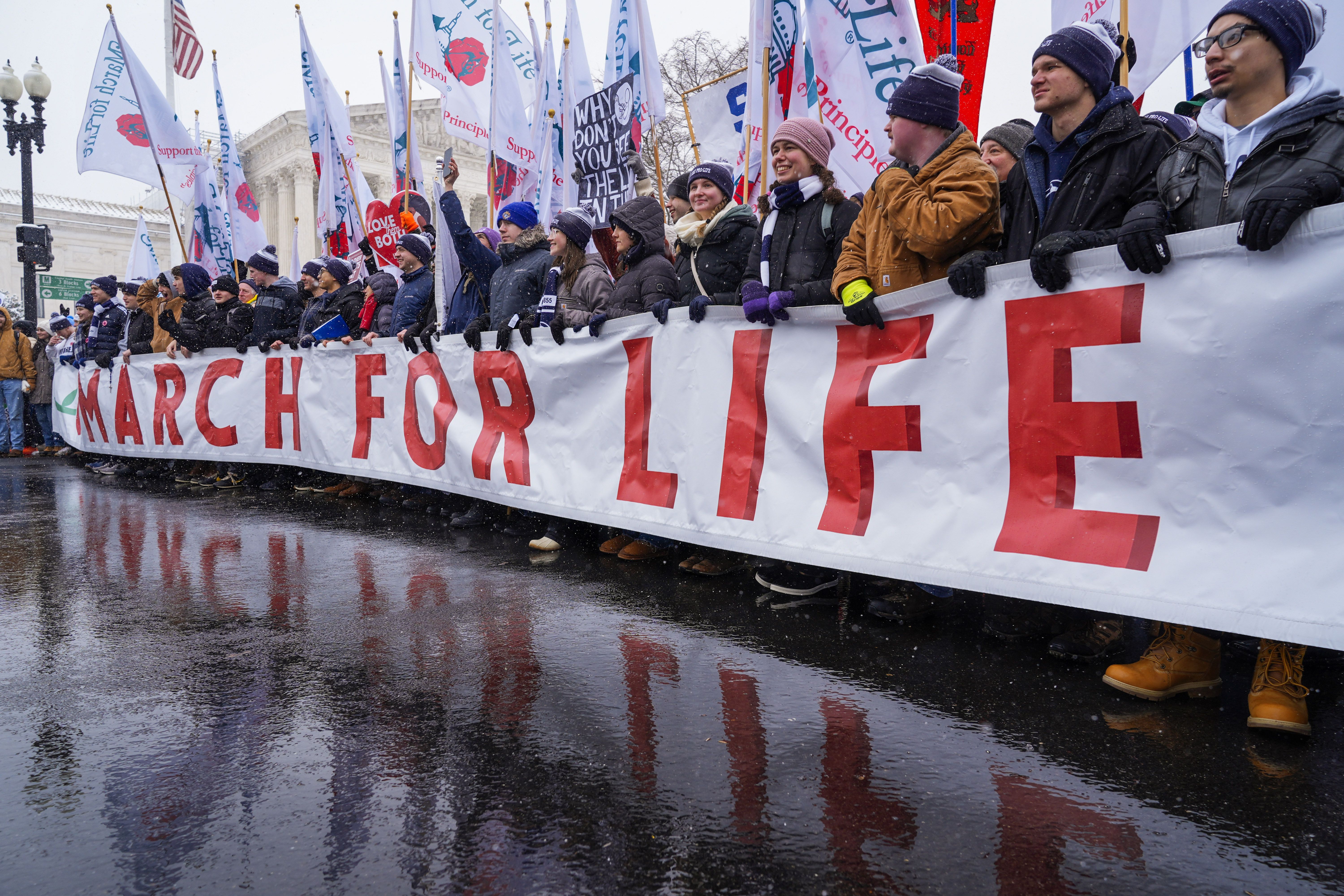 People holding the March for Life banner pause as they march past the Supreme Court on Friday in Washington.