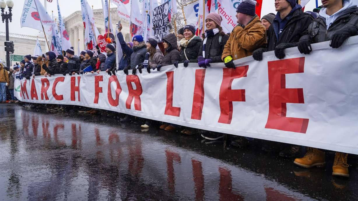 People holding the March for Life banner pause as they march past the Supreme Court on Friday in Washington.