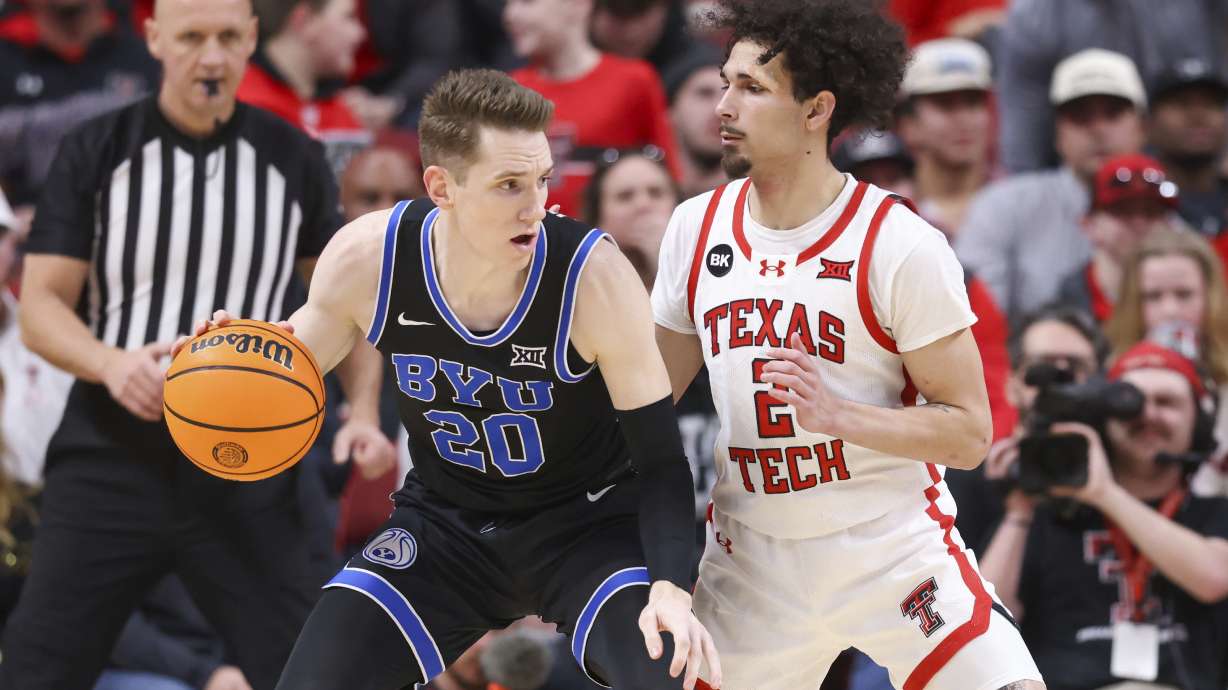 BYU guard Spencer Johnson (20) dribbles past Texas Tech guard Pop Isaacs (2) during the first half of an NCAA college basketball game, Saturday, Jan. 20, 2024, in Lubbock, Texas.