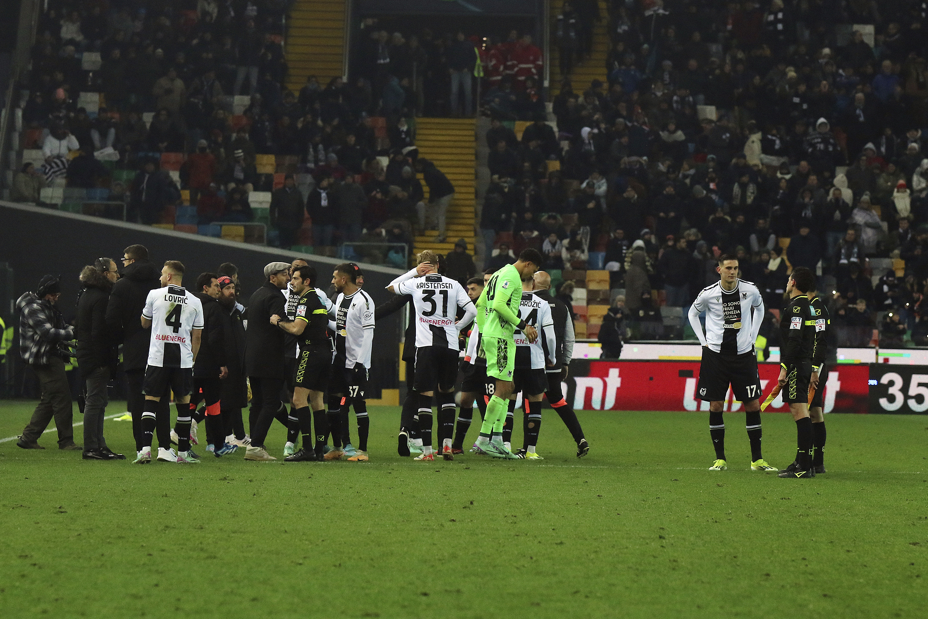 Referee Enzo Maresca, eight from left, match officials, right, and Udinese's players gather as the Italian Serie A soccer match between Udinese and AC Milan is suspended, at the Friuli stadium in Udine, Italy, Saturday, Jan. 20, 2024. Racist abuse aimed at AC Milan goalkeeper Mike Maignan prompted a top-tier Italian league game at Udinese to be suspended briefly during the first half. Maignan left the field after the insults which followed a goal for Milan.