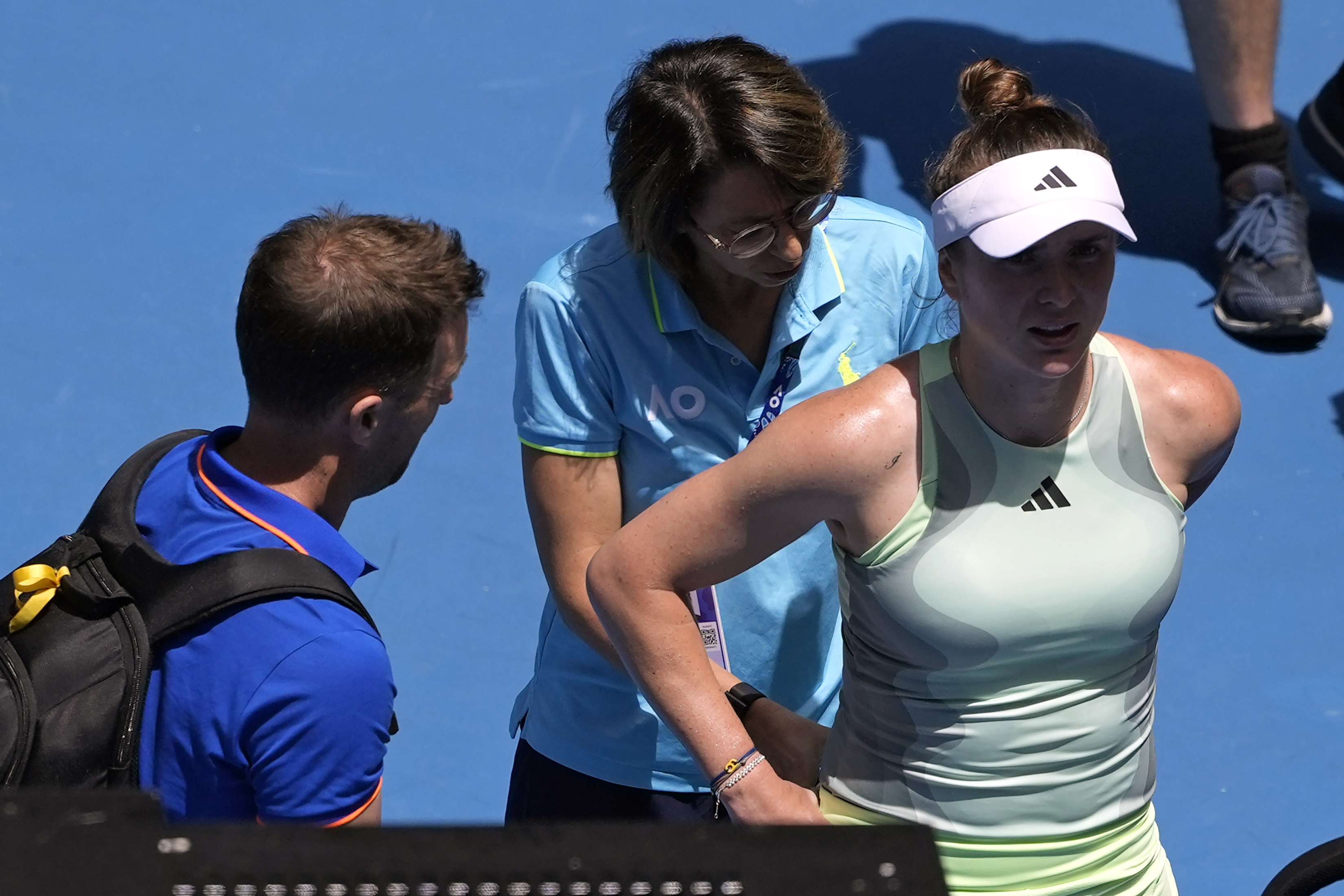 Elina Svitolina of Ukraine receives treatment from a trainer before retiring from her fourth round match against Linda Noskova of the Czech Republic at the Australian Open tennis championships at Melbourne Park, Melbourne, Australia, Monday, Jan. 22, 2024. 