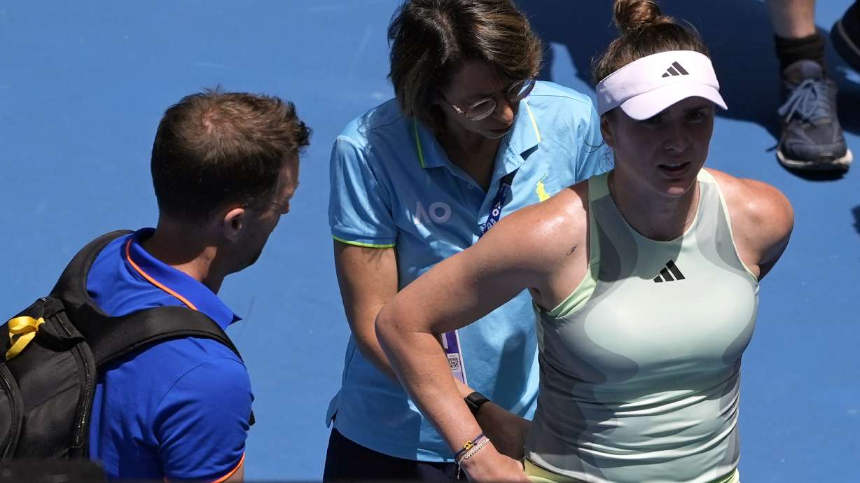 Elina Svitolina of Ukraine receives treatment from a trainer before retiring from her fourth round match against Linda Noskova of the Czech Republic at the Australian Open tennis championships at Melbourne Park, Melbourne, Australia, Monday, Jan. 22, 2024.