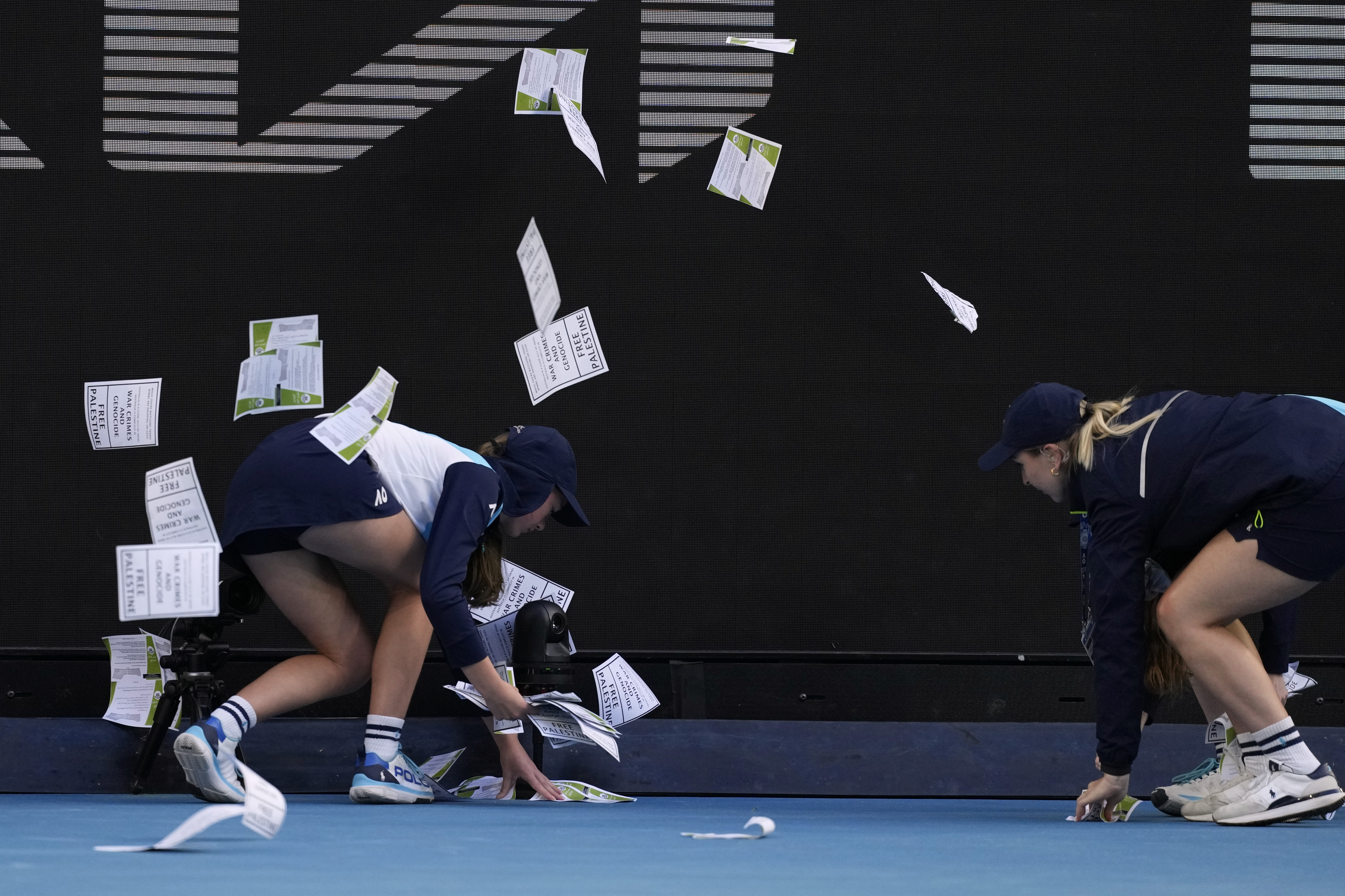 Ball kids pickup "free Palestine" leaflets thrown onto Margaret Court Arena during the fourth round match between Alexander Zverev of Germany and Cameron Norrie of Britain at the Australian Open tennis championships at Melbourne Park, Melbourne, Australia, Monday, Jan. 22, 2024. 