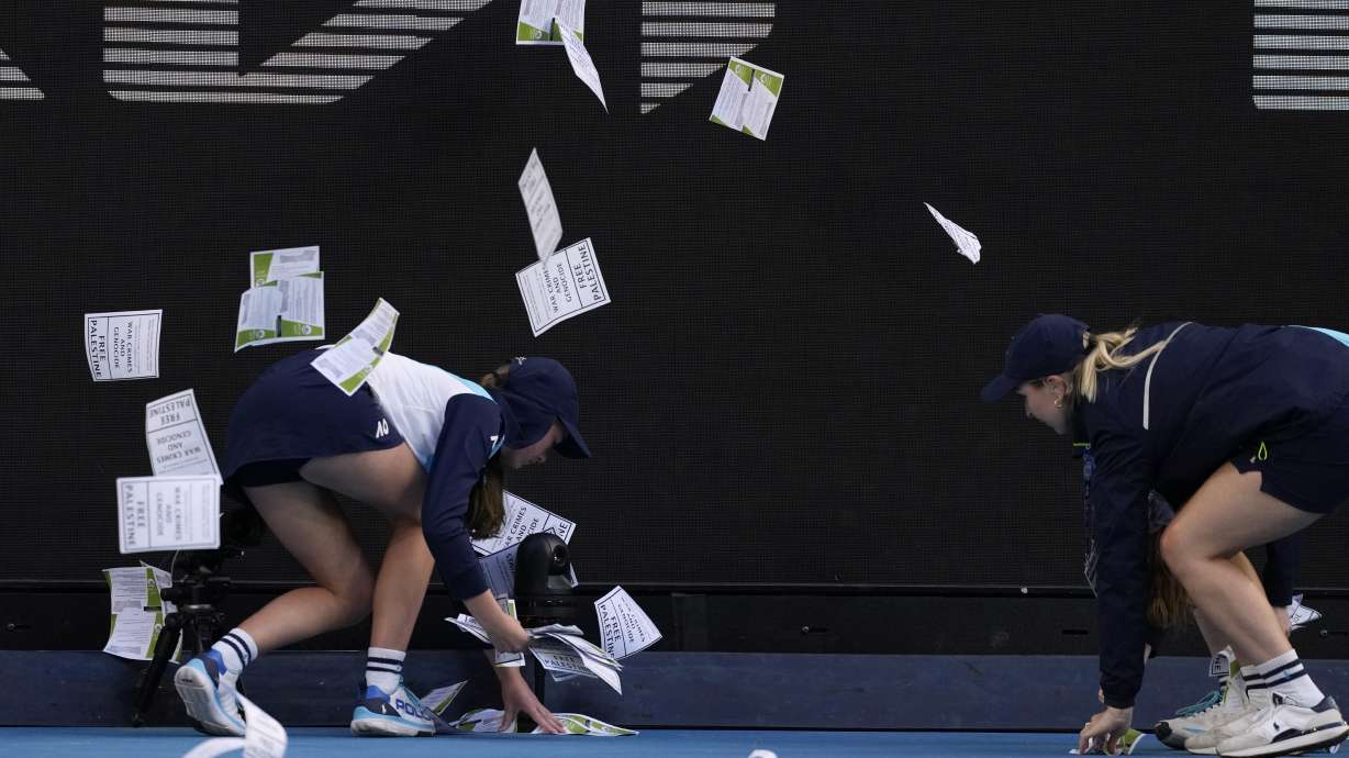 Ball kids pickup "free Palestine" leaflets thrown onto Margaret Court Arena during the fourth round match between Alexander Zverev of Germany and Cameron Norrie of Britain at the Australian Open tennis championships at Melbourne Park, Melbourne, Australia, Monday, Jan. 22, 2024.
