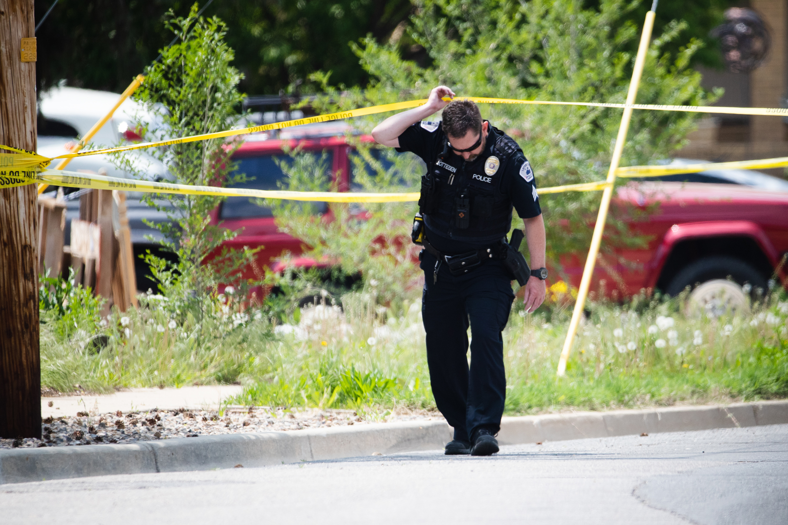 A Layton police officer crosses police tape at the scene of a triple homicide in Layton on May 19, 2023.