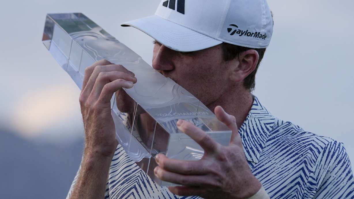 Nick Dunlap kisses the trophy after winning the American Express golf tournament, Sunday, Jan. 21, 2024, in La Quinta, Calif.