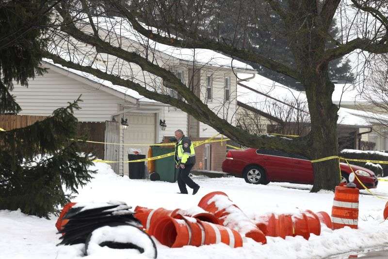 A Joliet police officer surveys a crime scene Tuesday. A man suspected of shooting and killing eight people in suburban Chicago fatally shot himself after a confrontation with law enforcement officials at a gas station in Texas, where he had no known ties, authorities said.