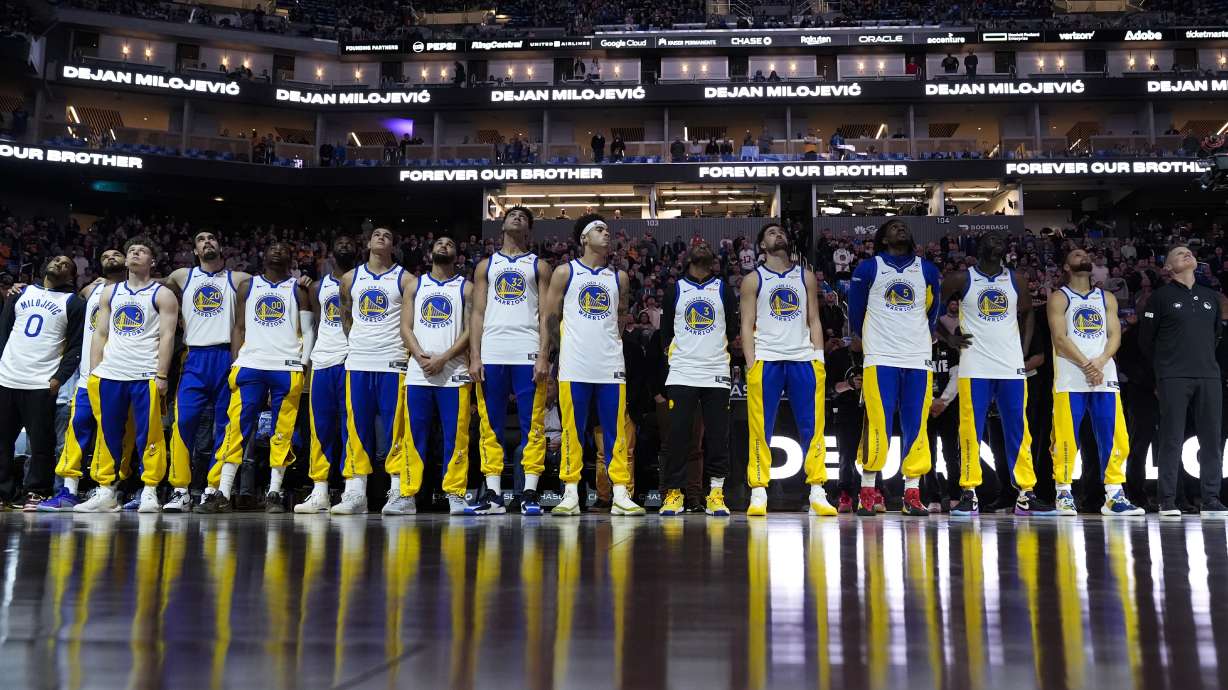 The Golden State Warriors watch a video tribute to late assistant coach Dejan Milojevic, who died Jan. 17 after suffering a heart attack, before an NBA basketball game against the Atlanta Hawks, Wednesday, Jan. 24, 2024, in San Francisco.