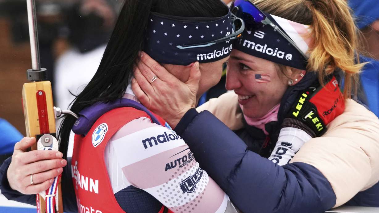 FILE - Joanne Reid, left, of United States, and compatriot Deedra Irwin embrace at the finish line during the women's 4 x 6 km relay race at the biathlon World Cup in Anterselva, Italy, Jan. 22, 2022. The United States Biathlon national champion was sexually harassed and abused for years by a ski-wax technician while racing on the sport's elite World Cup circuit, investigators found. When the two-time Olympian complained, Reid said she was told his behavior was just part of the male European culture.