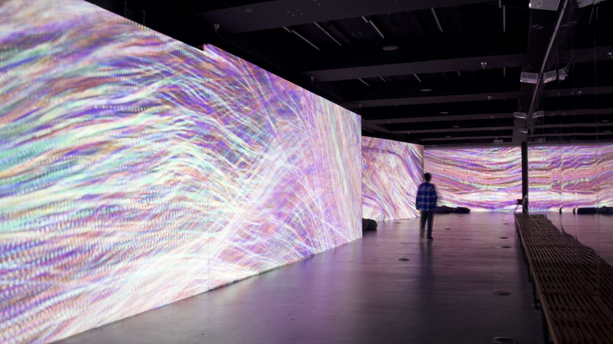 A visitor walks past one of the wall panels during the immersive light show segment of the new "Into the Mind of Artificial Intelligence" exhibit at The Leonardo museum in Salt Lake City on Friday.